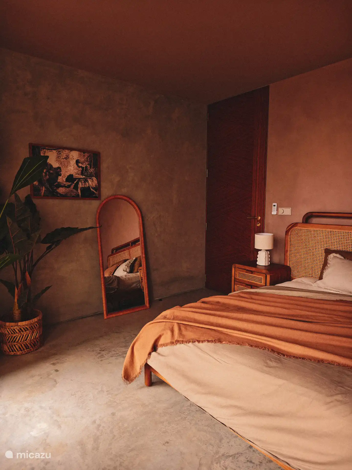 Bedroom with kigsize teak bed and outdoor seating area with partial sea view.