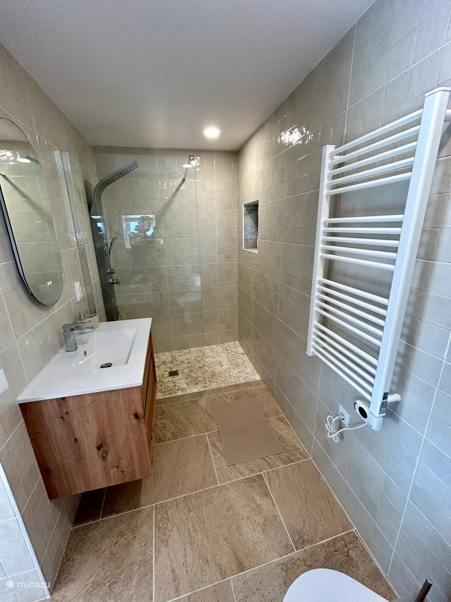 Volledige badkamer, met rainshower, massage stralen, toilet, radiator, wastafel, spiegel met led verlichting en ontwazeming en een föhn aanwezig 