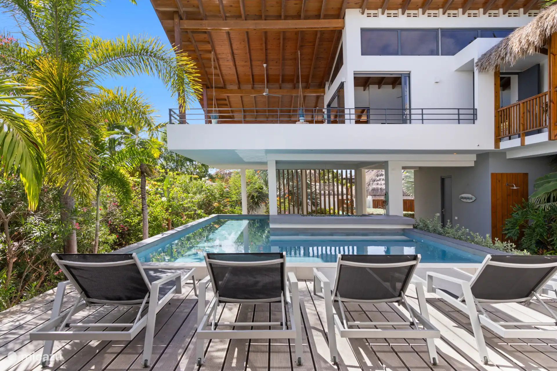 Zwembad, uitzicht op veranda en woonkamer. Ook te zien dat de voorkant van het zwembad door middel van houten palen is voorzien van privacy