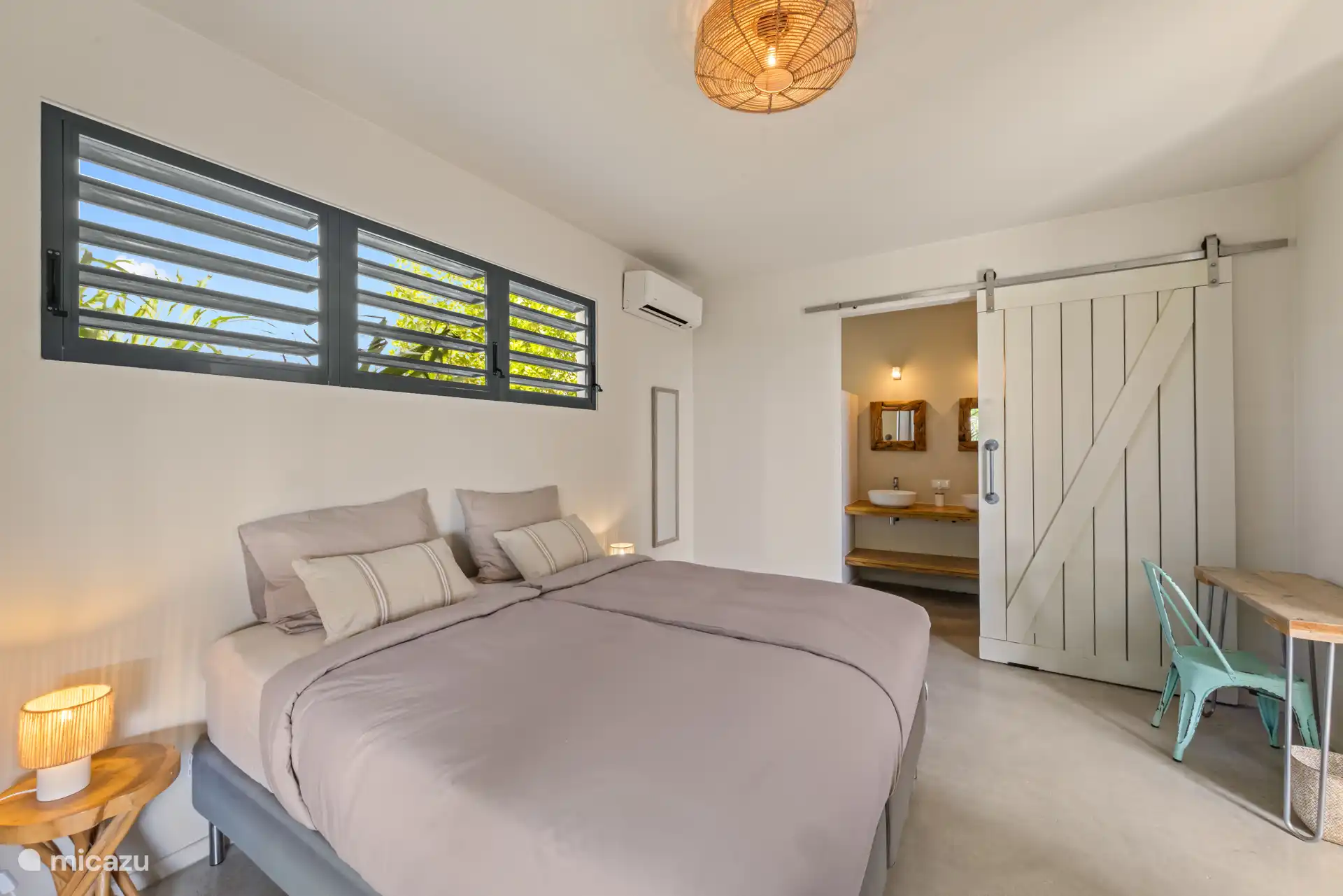 Slaapkamer 1 met shutters en muggengaas, doorkijkje naar de ensuite prive badkamer
