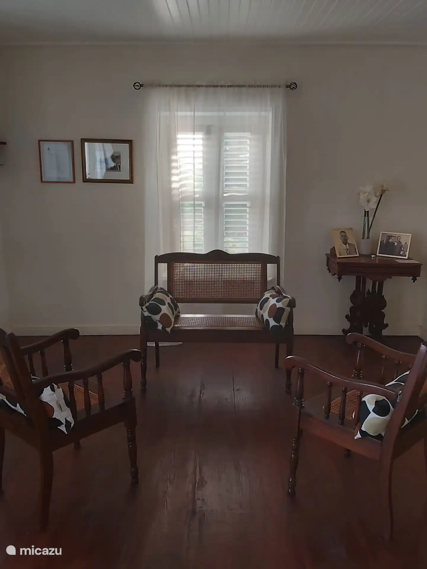 De ontvangstzaal met in het midden en shutterraam met zicht op de tuin, regenbak en de hoofdweg.