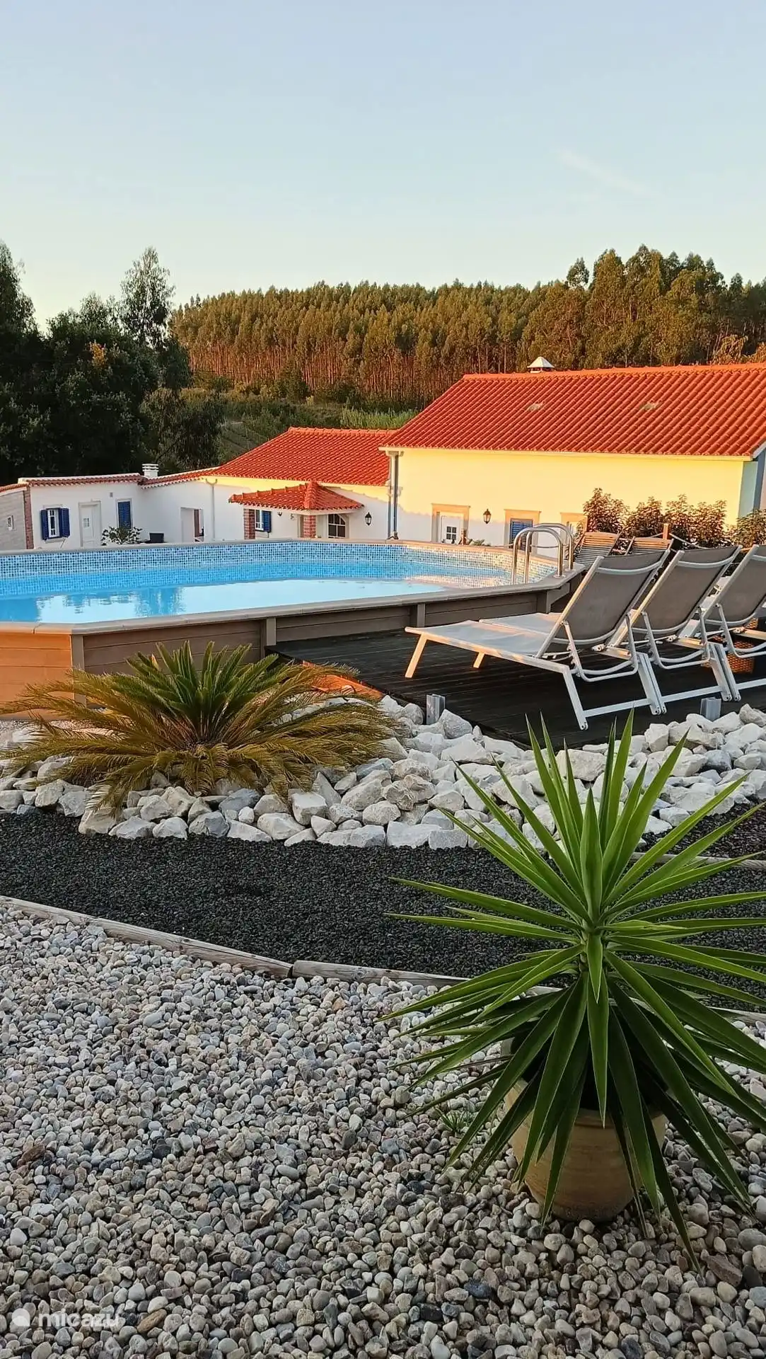 Zicht vanop een dele van het buitenterras van Casa Anna op het zwembad en op het hoevecomplex