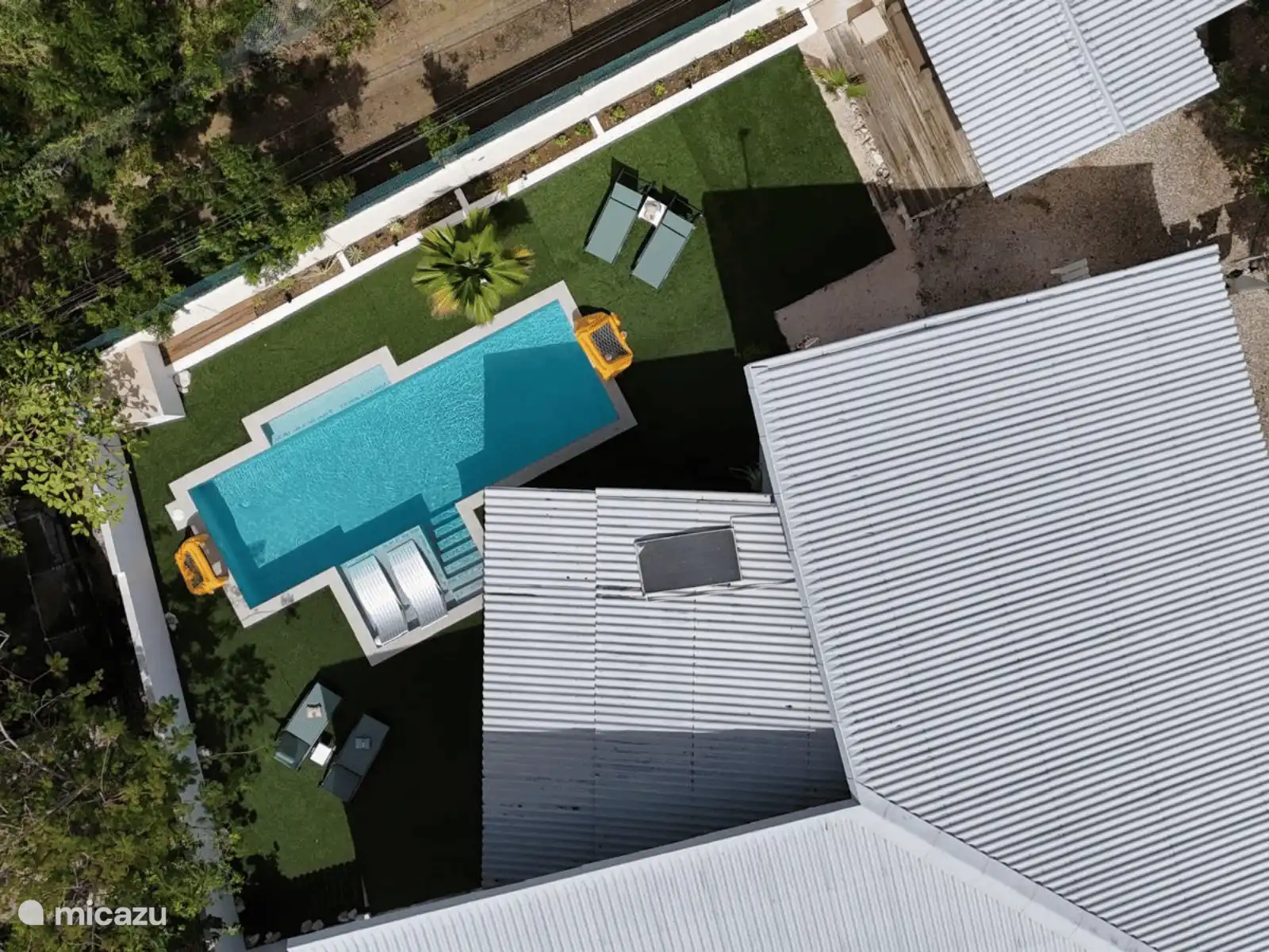 Vista en diagonal de la villa: piscina privada, zonas para tomar el sol y mucha vegetación. Puedes ver inmediatamente cuánto espacio y privacidad tienes aquí.