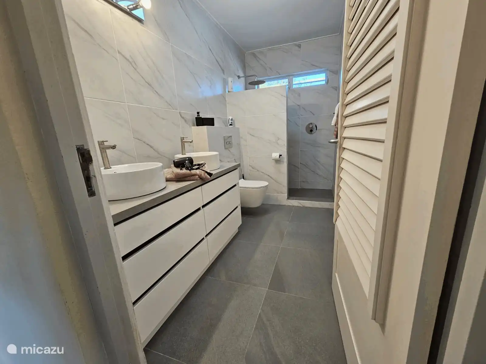 Baño lujoso con lavabo doble y ducha espaciosa a pie de casa. Fresco, moderno e ideal si te alojas en grupo.