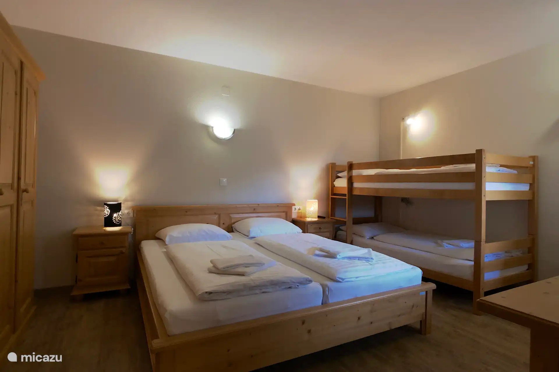 Slaapkamer met twee persoonsbed, stapelbed en eigen badkamer.