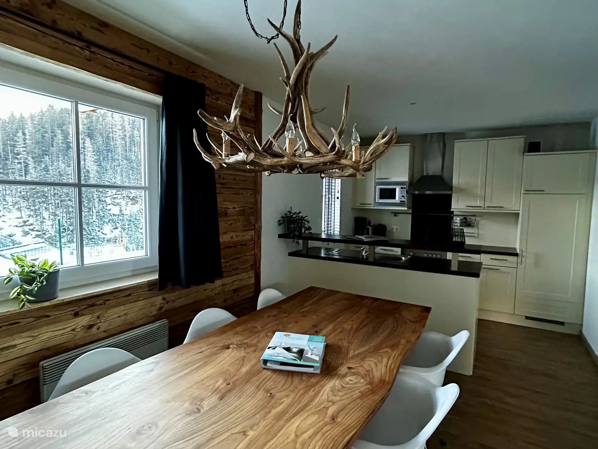Woonkamer met uitzicht op de tuin en het dal. Open keuken met eettafel.