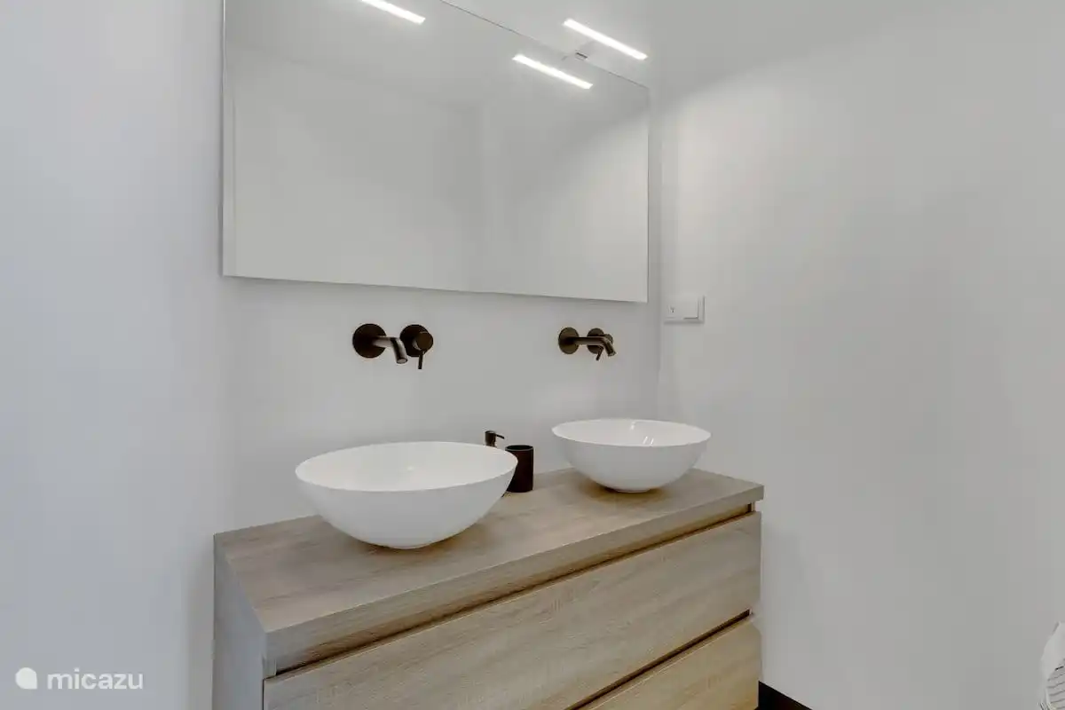 Badezimmermöbel mit zwei Waschbecken und einem großen Spiegel.