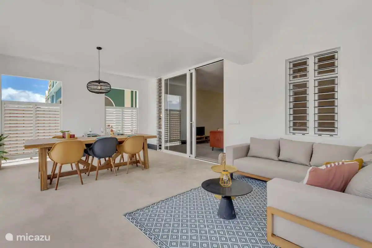 Überdachte Veranda mit Wohnzimmer, Esstisch und Zugang zum Wohnzimmer.