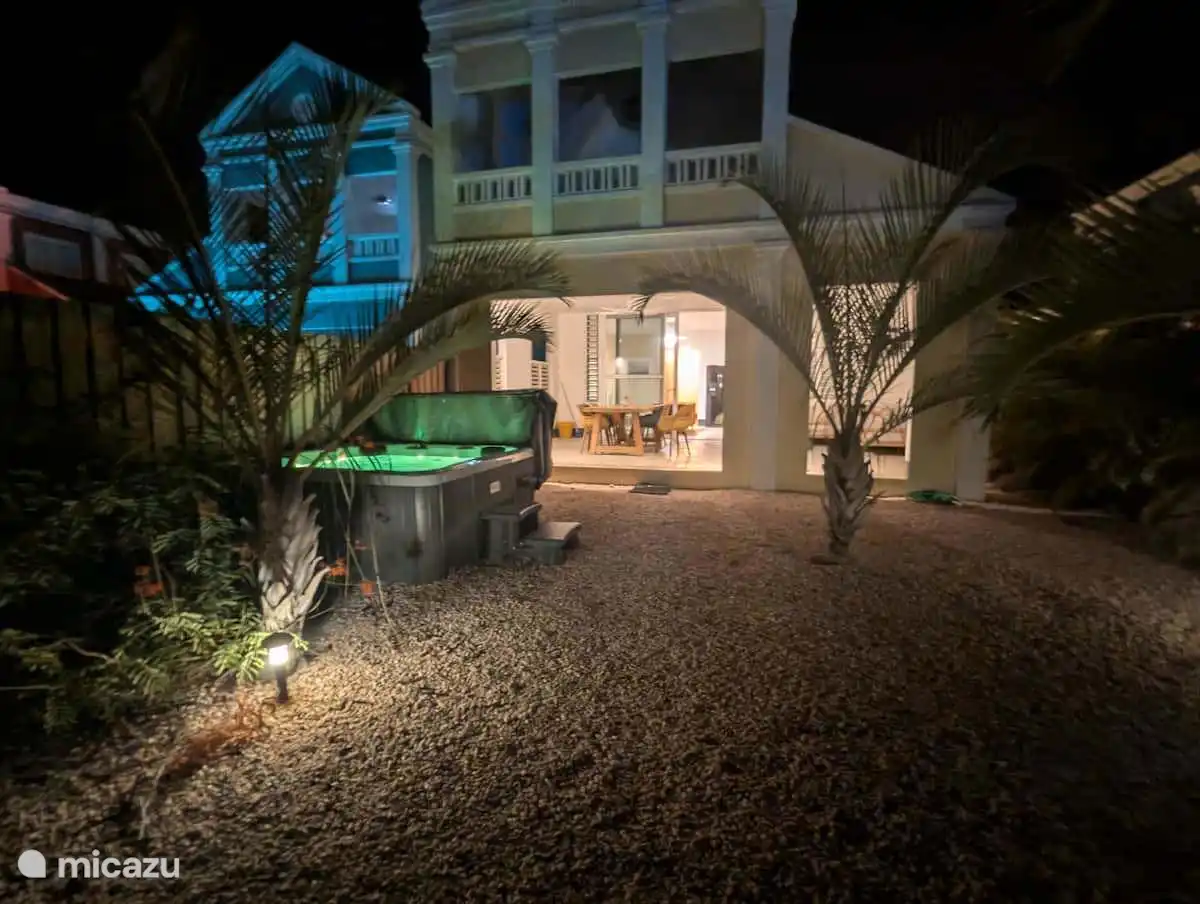 Der Garten, der Jacuzzi und die überdachte Veranda am Abend.