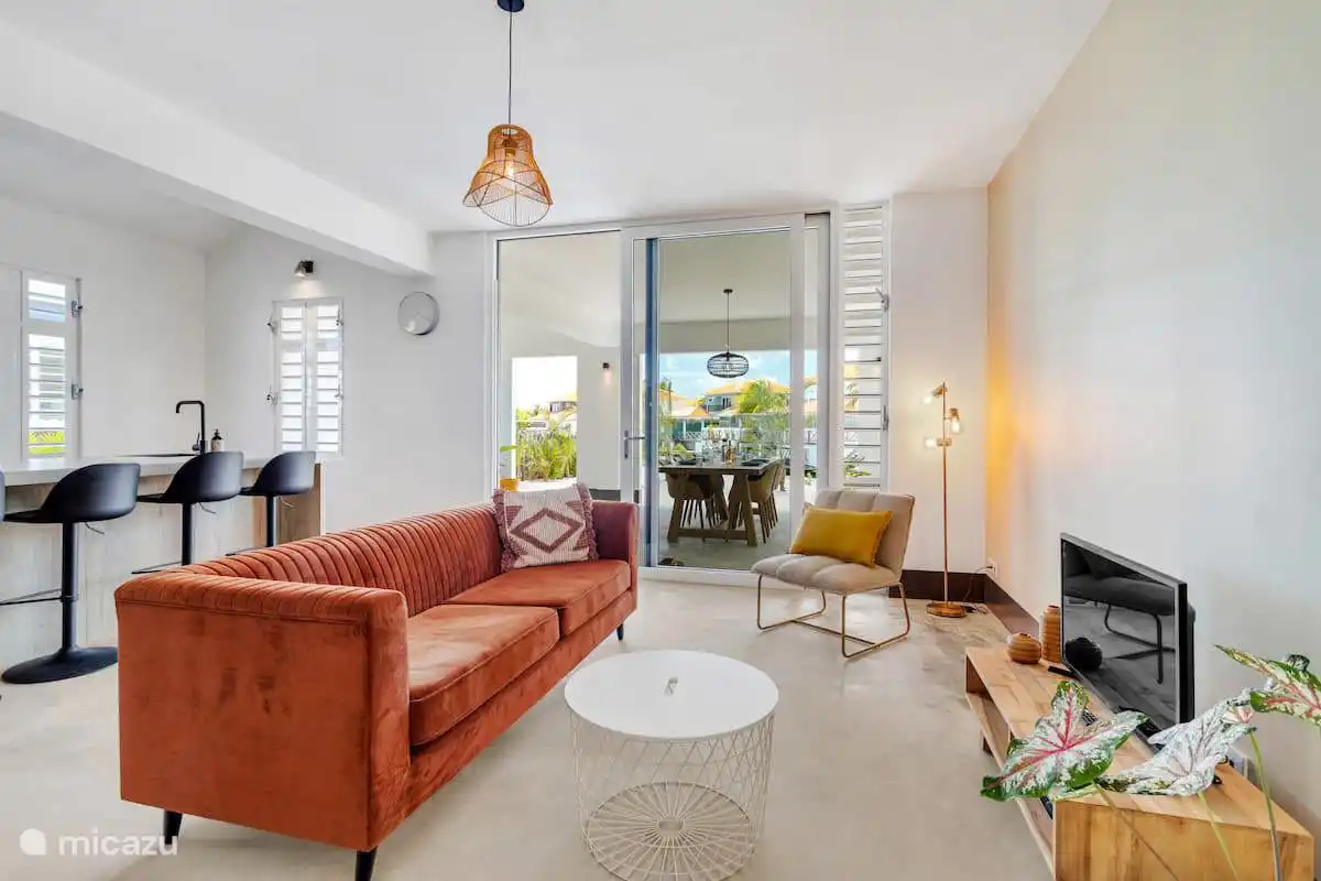 Wohnzimmer mit Sitzecke, Fernseher und Schiebetüren zur überdachten Veranda.