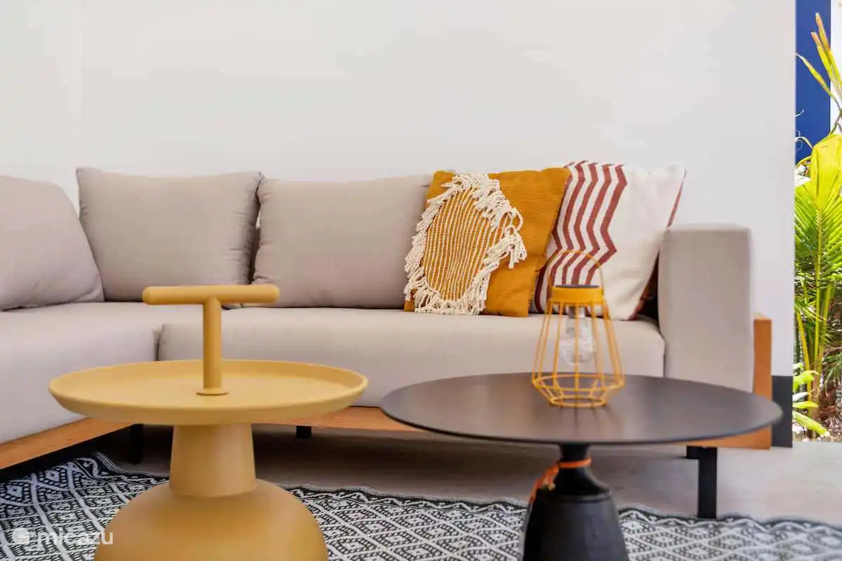 Lounge-Sofa mit Kissen und Beistelltischen auf der Veranda.