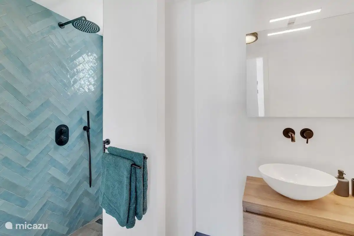 Badezimmer mit begehbarer Dusche und Waschbecken.