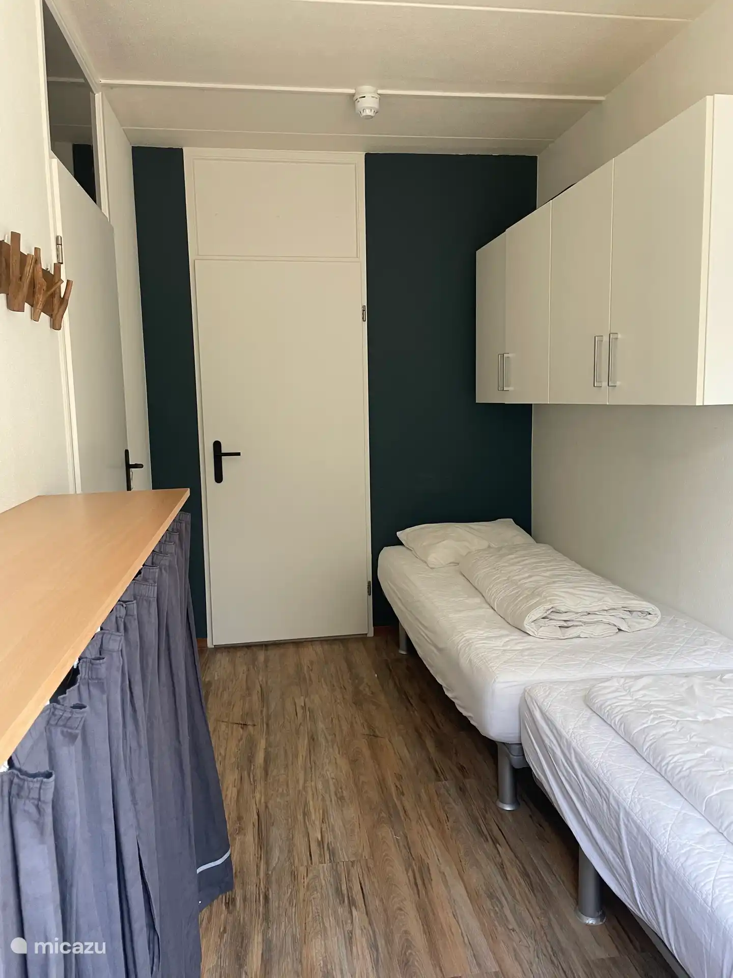 slaapkamer met drie bedden en toegang tot grote badkamer met ligbad.