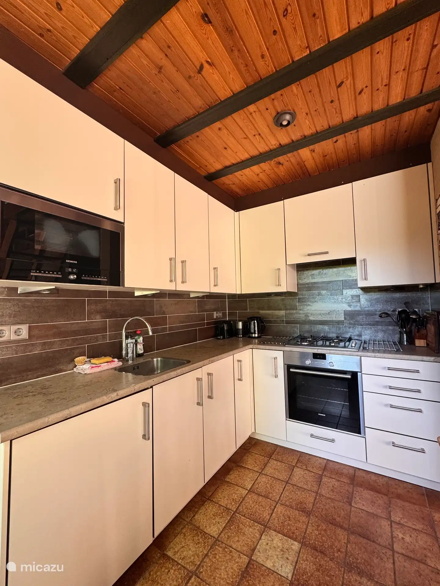 Keuken met oven, magnetron, gasformuis, koffiezet-apparaat en wasterkoker. 
