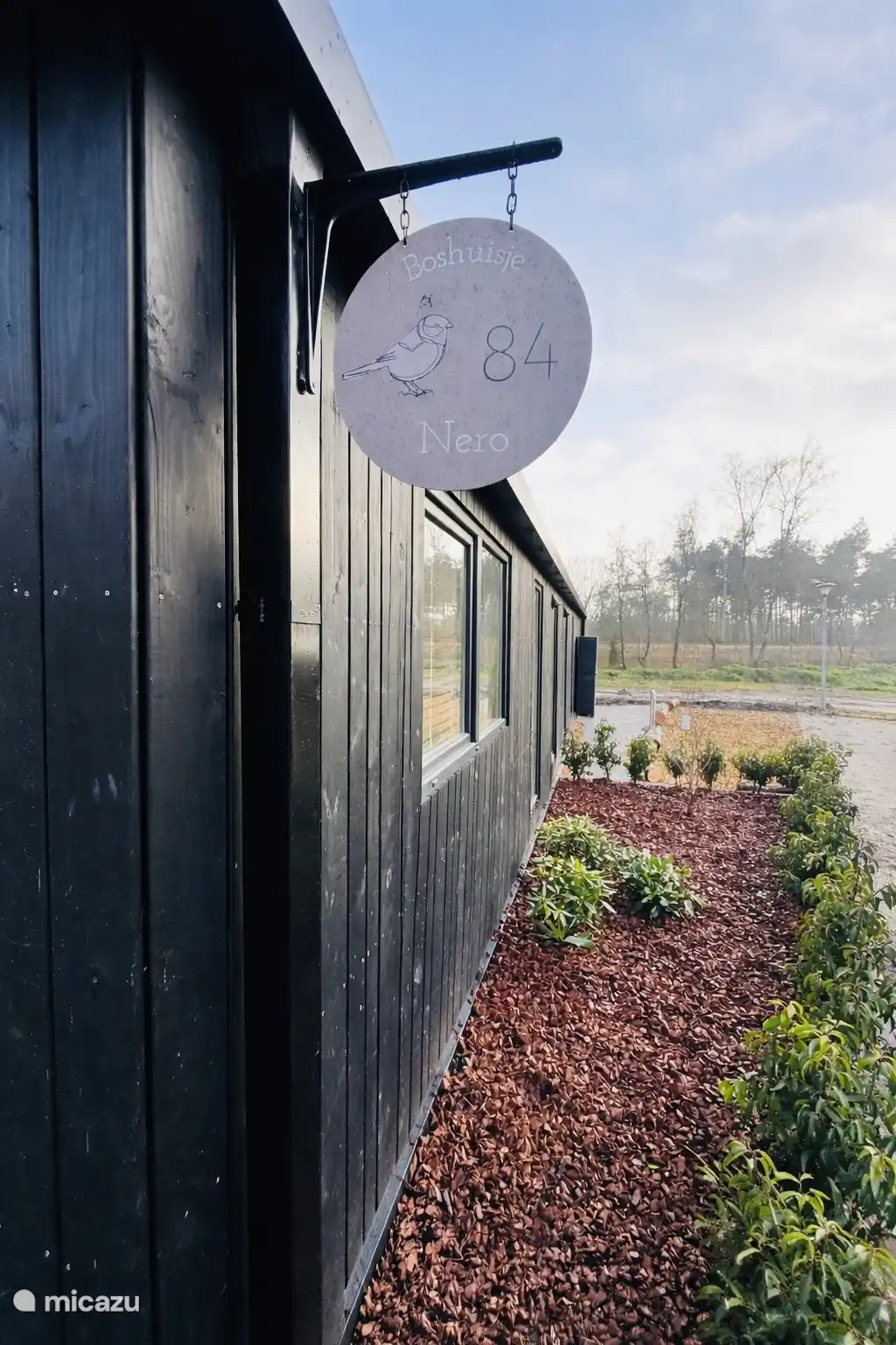 Zijkant Boshuisje Nero met twee privé parkeerplaatsen en fietsnietje waar je een slot aan vast kan maken 