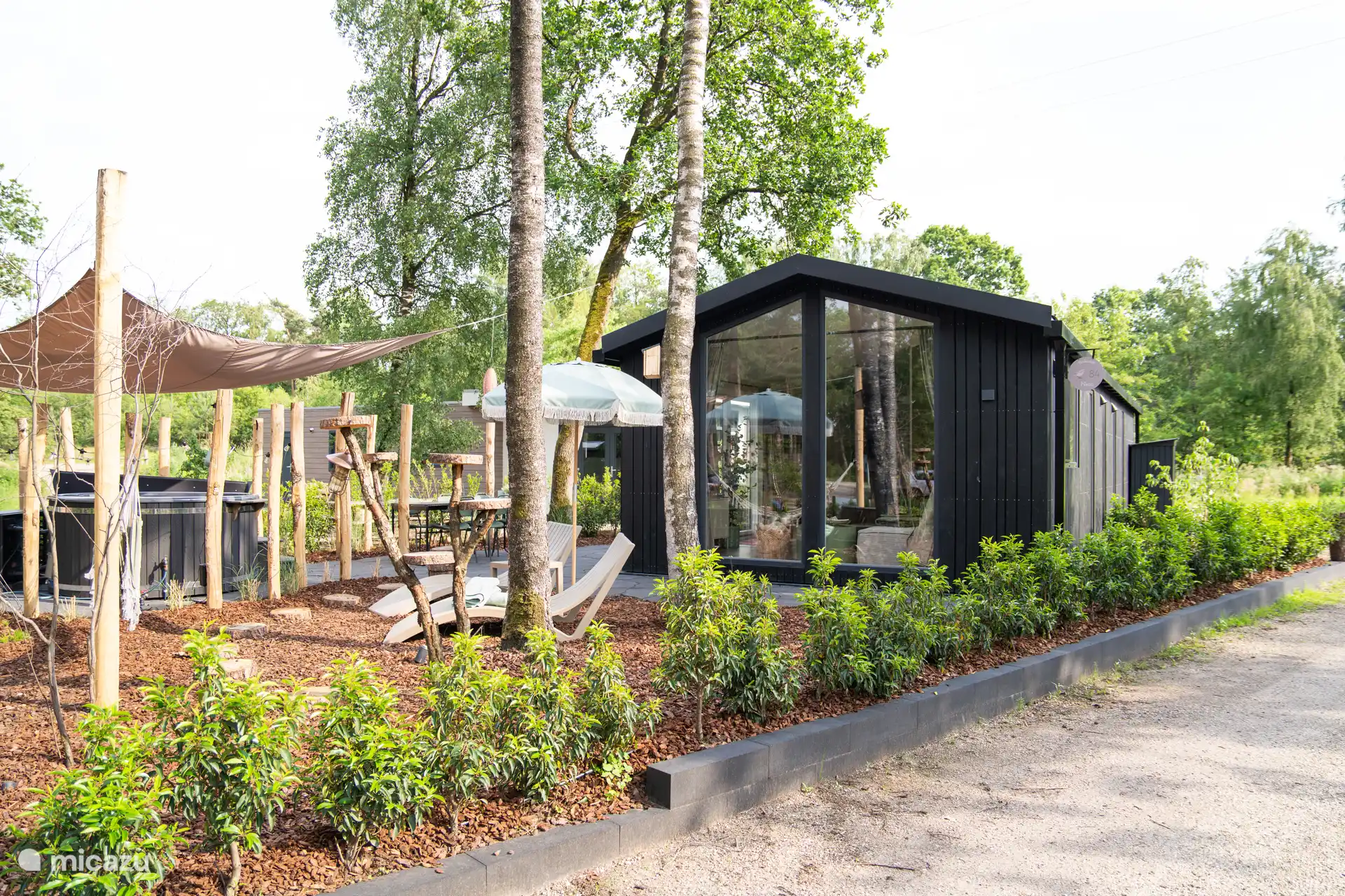 Front view Forest cottage Nero with hot tub, hammock, lounge chairs in a private garden 