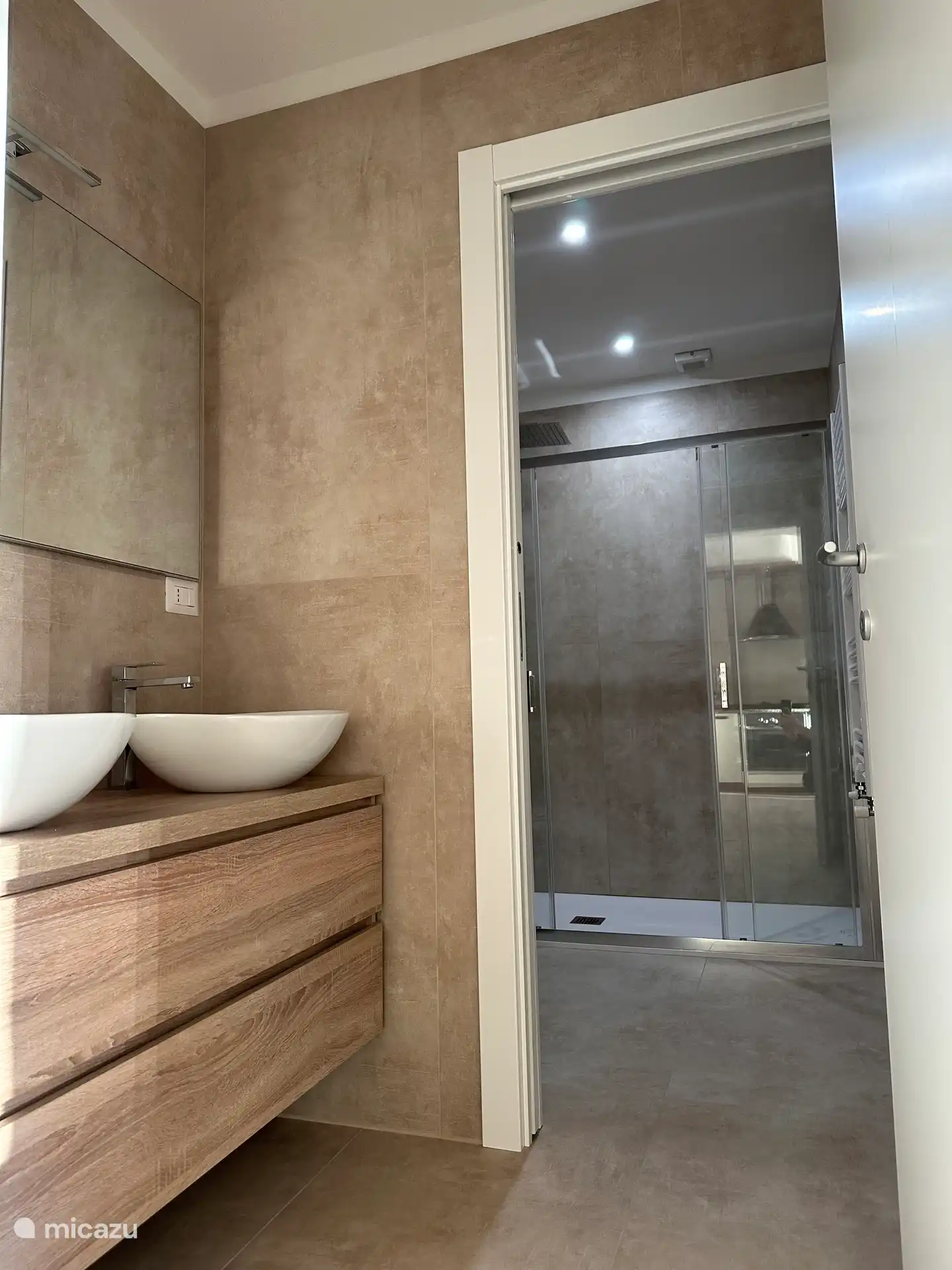 Salle de bain avec porche avec 2 lavabos. Toilettes et douche à l’italienne accessibles par porte coulissante.