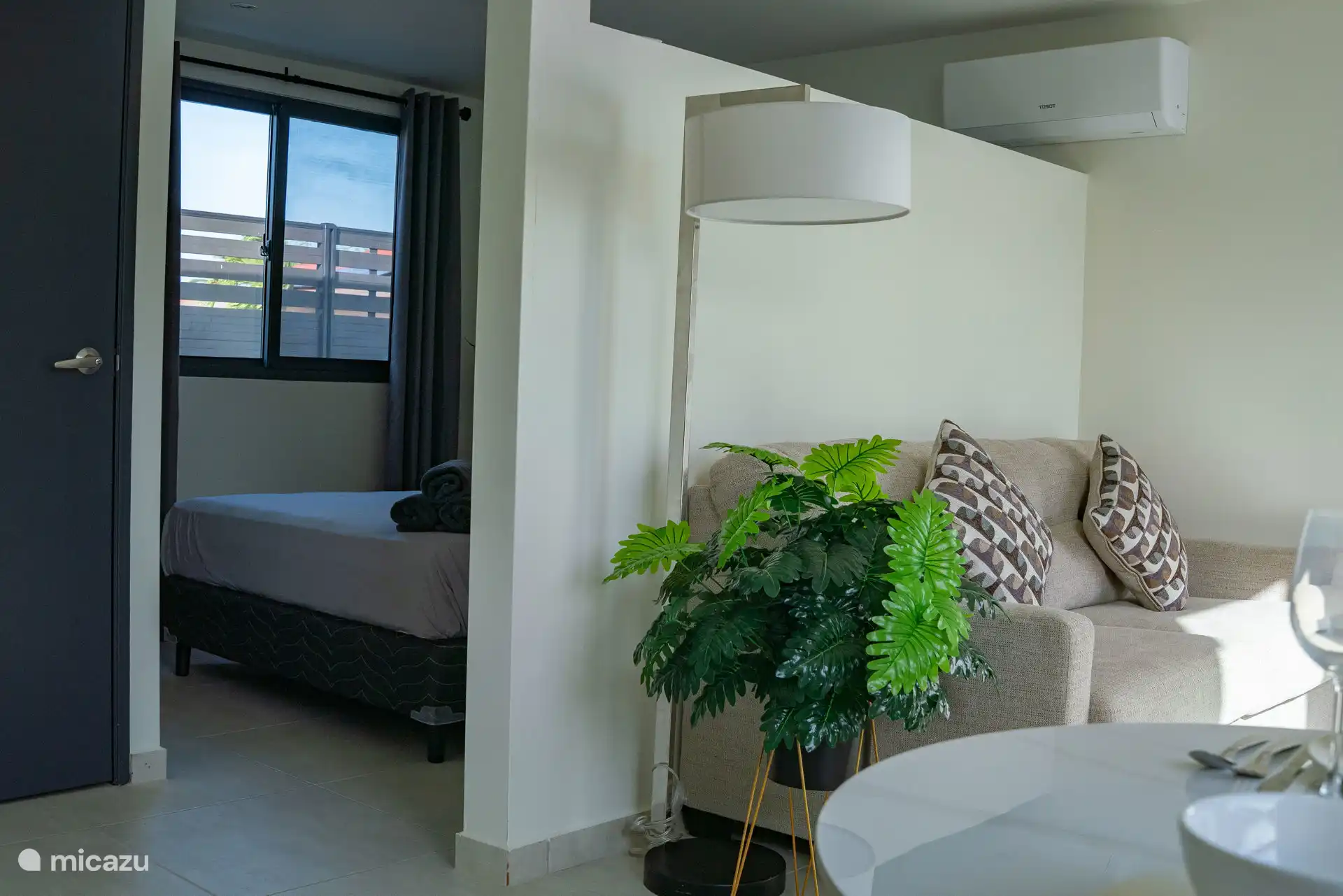 Overzicht van de woonkamer met doorkijk naar de slaapkamer, wat zorgt voor een open en ruimtelijk gevoel.