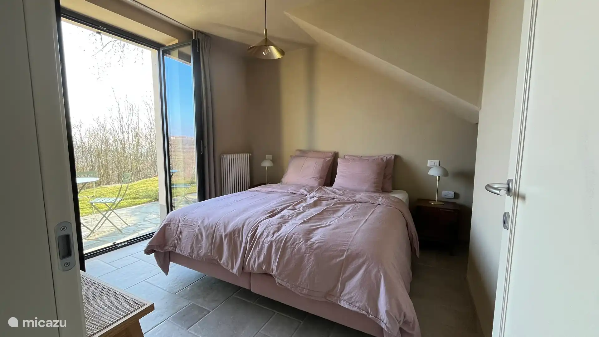 Slaapkamer met openslaande deuren naar terras en tuin.