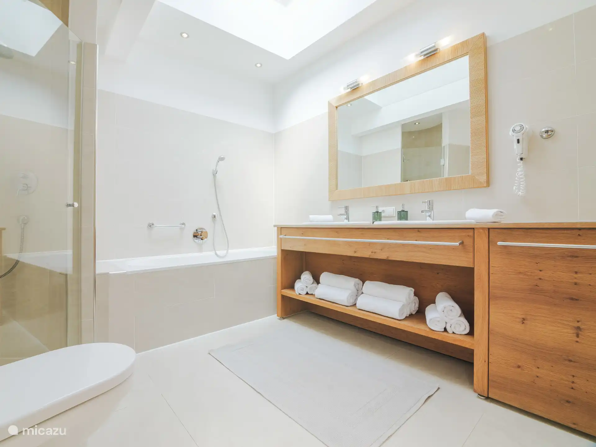 Badkamer met douche, bad en toilet. Er is ook een apart toilet in het appartement.
