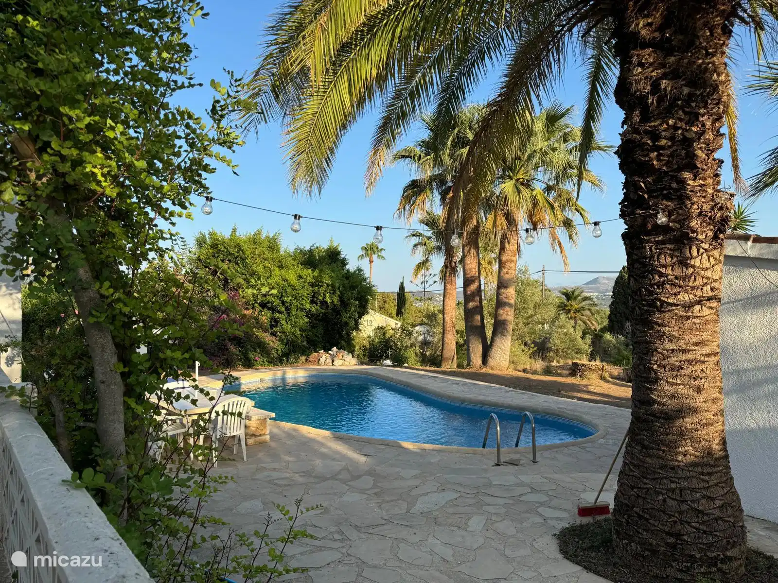 Het terras rond het zwembad, met rechts het 'poolhouse' (met douche en toilet voor bij het zwembad)