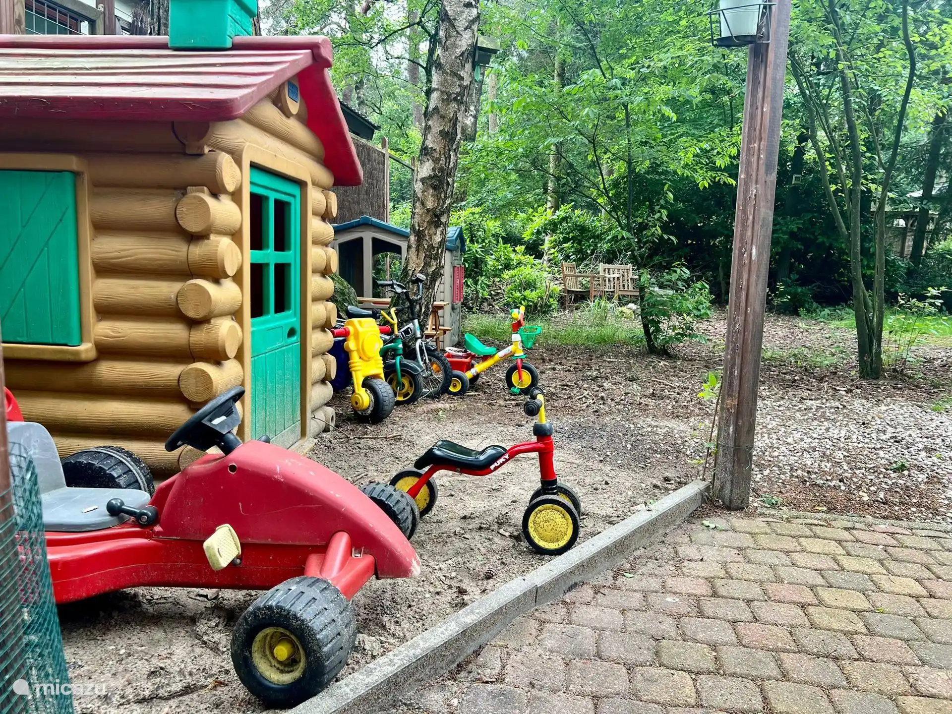 Fahrautos und Fahrräder im eingezäunten Garten