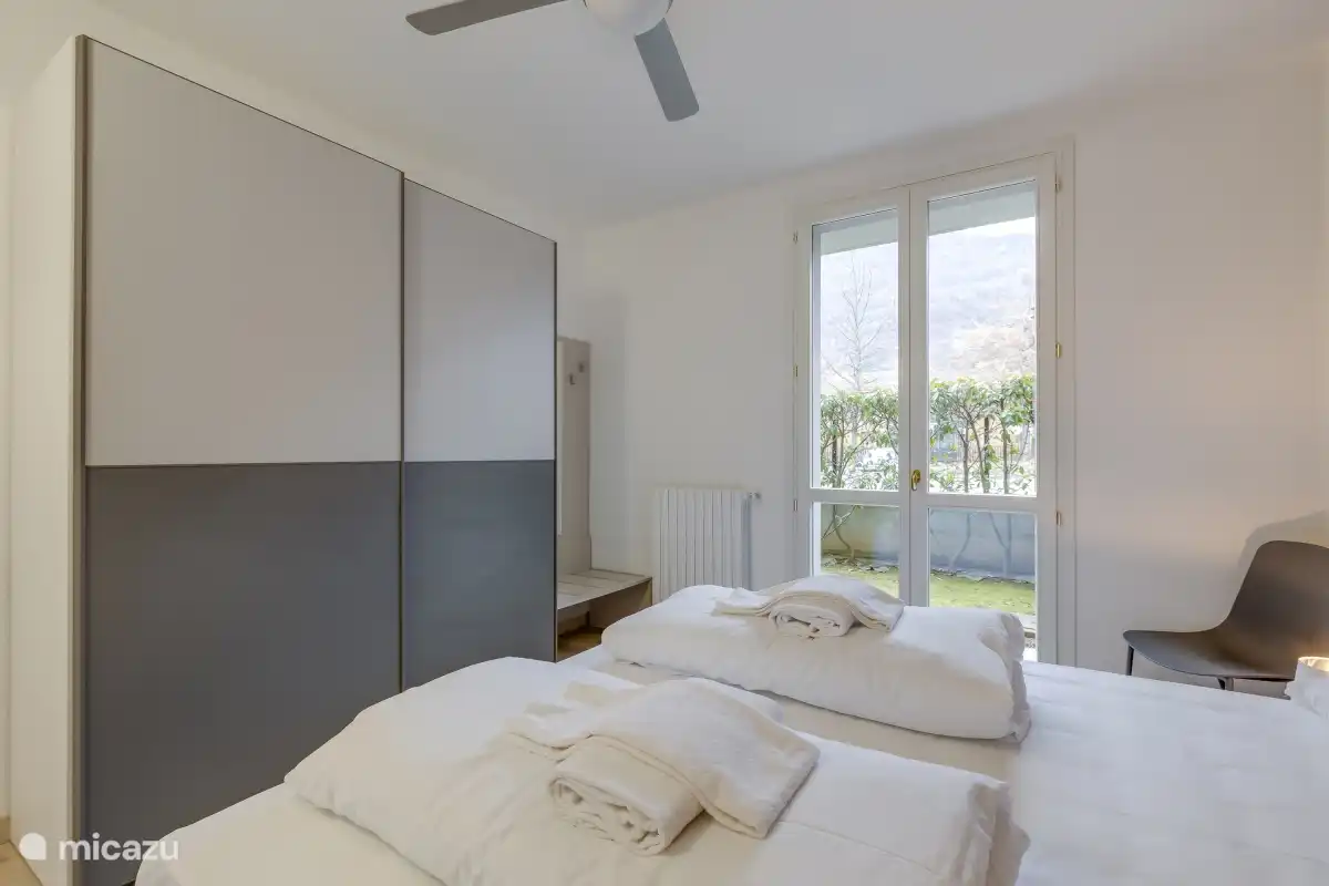 Masterbedroom met openslaande deuren naar de tuin achterzijde en plafondventilator