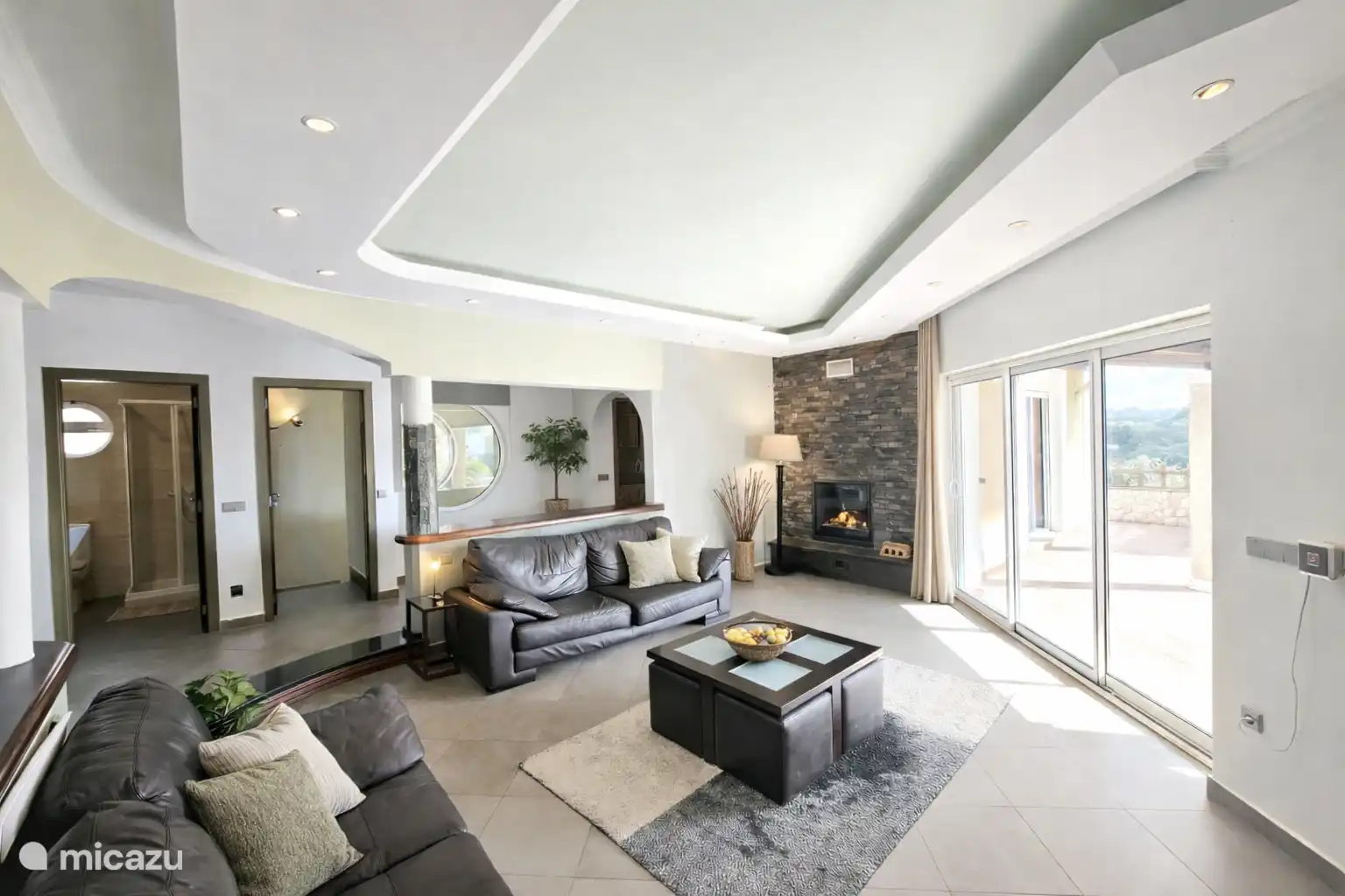 Woonkamer voorzien van 2- en 3zitsbank, openhaard, salontafel met 4 zitpoefjes, airco en sfeerverlichting.