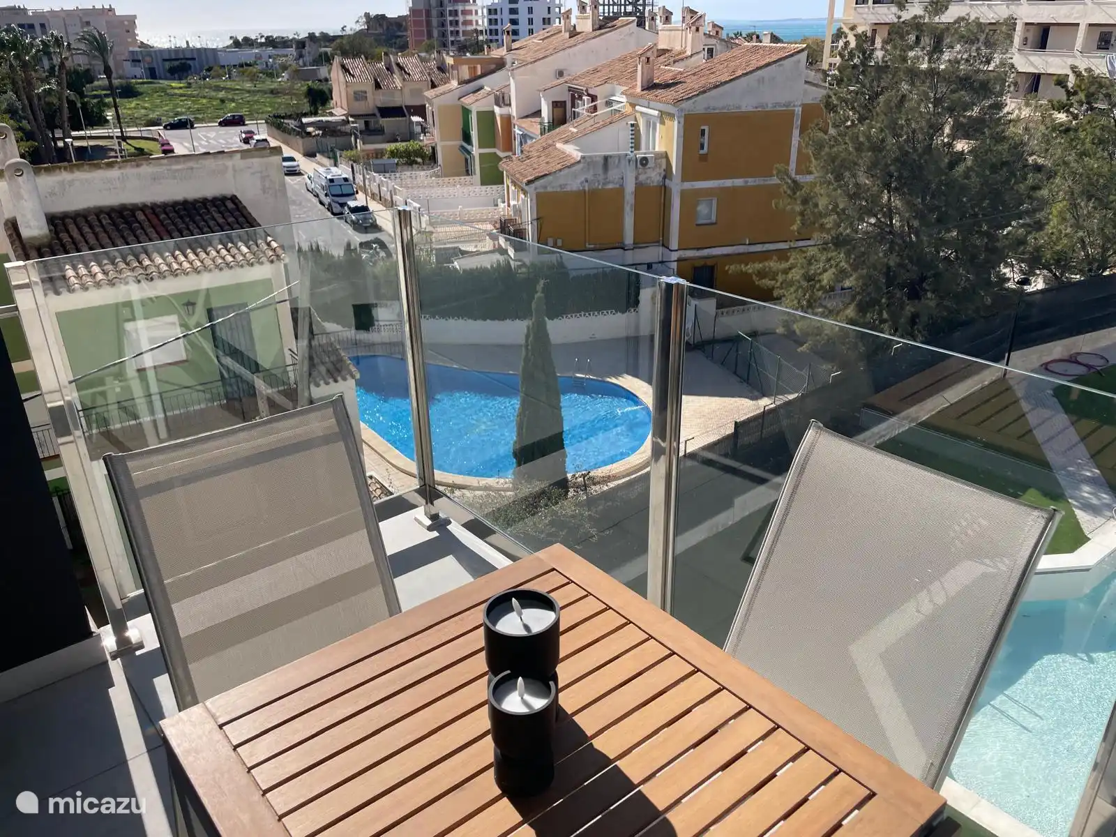 Balkon met uitzicht op het zwembad en op zee, waar je 's avonds mooi de lichtjes kan zien