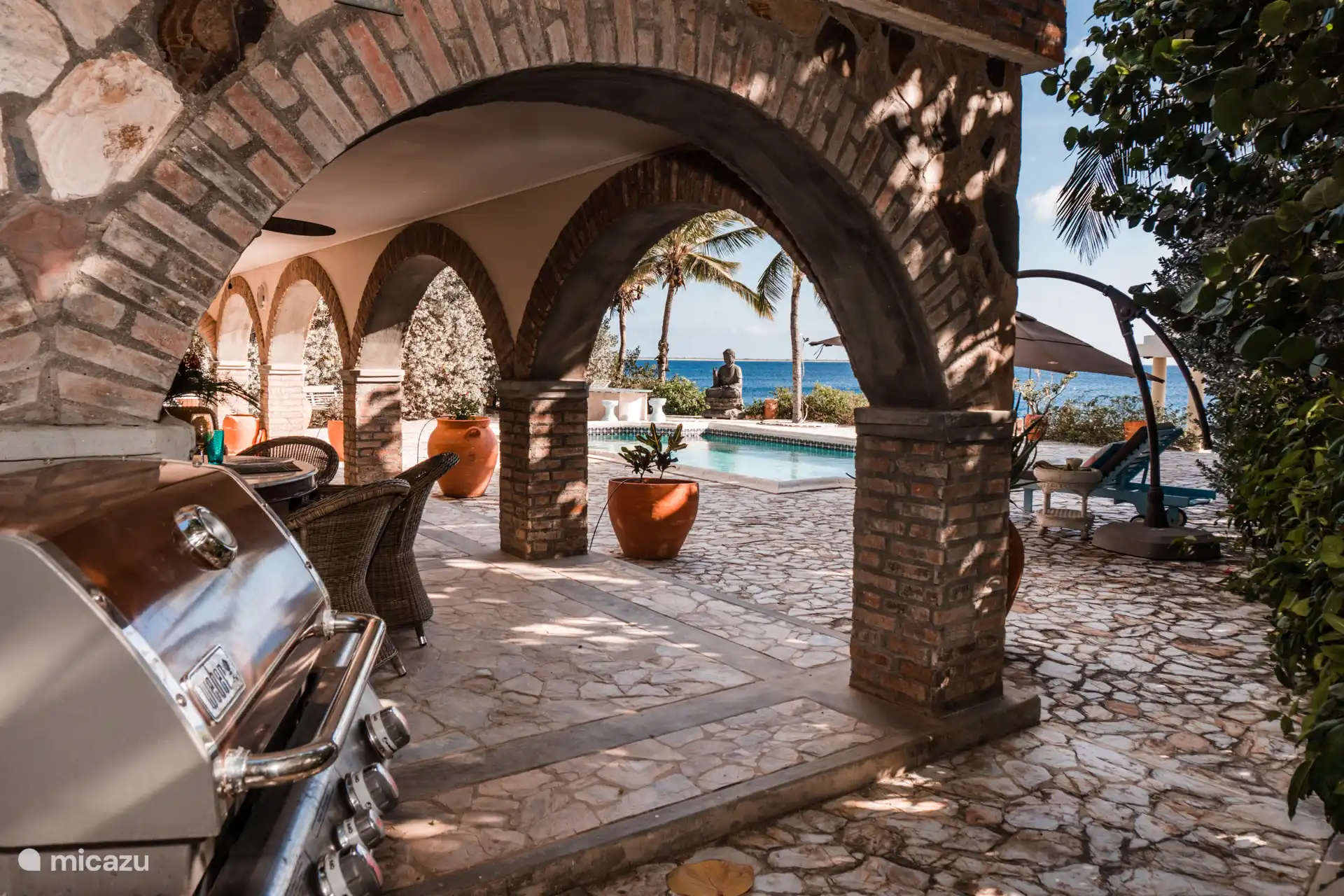 Terrasse mit Grill und Blick über Pool und Meer