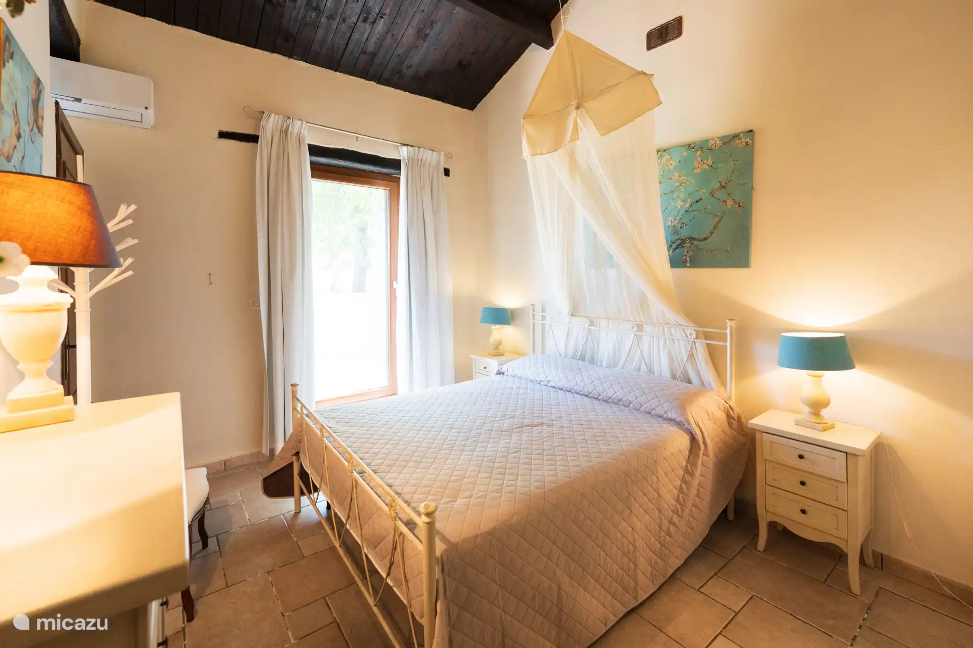 Slaapkamer 2 aan de linkerkant van het huis is rustig en licht ingericht, met een tweepersoonsbed en airconditioning. Een fijne kamer om koel en ontspannen te slapen.