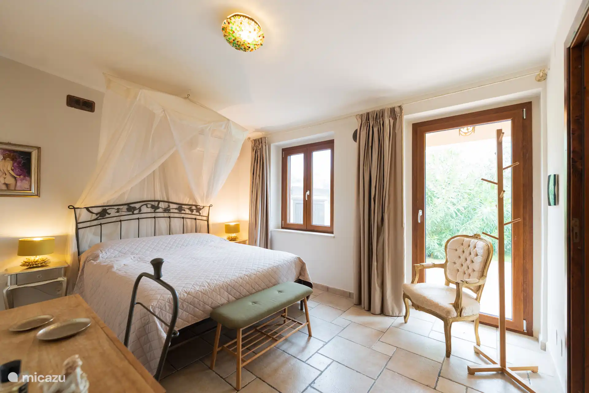 Slaapkamer 1 aan de rechterkant van het huis, met een tweepersoonsbed, zithoekje, badkamer en directe toegang naar buiten. Een rustige plek om wakker te worden.