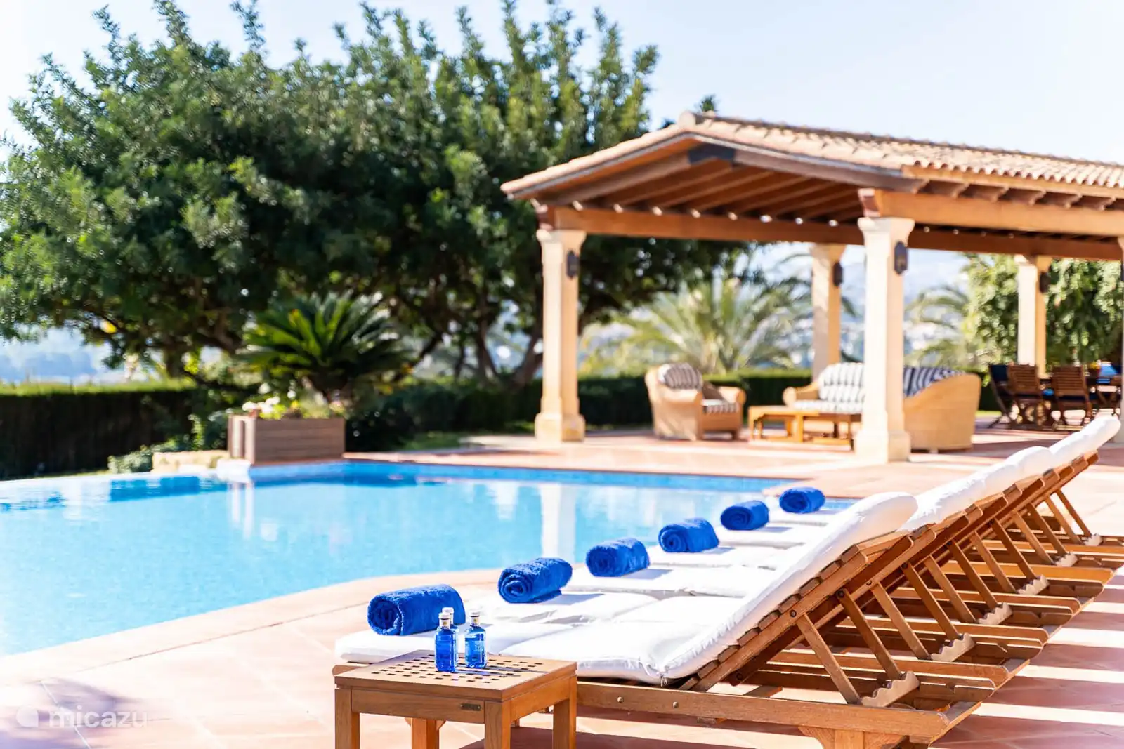 Belle et grande piscine, vue mer, terrasse avec chaises longues. Salon extérieur et lounge sur la terrasse couverte. 