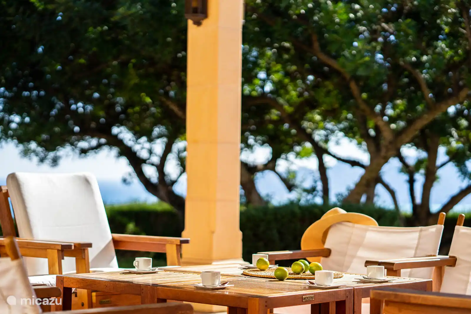 Salon extérieur sous la terrasse couverte, face à la piscine et la vue panoramique.