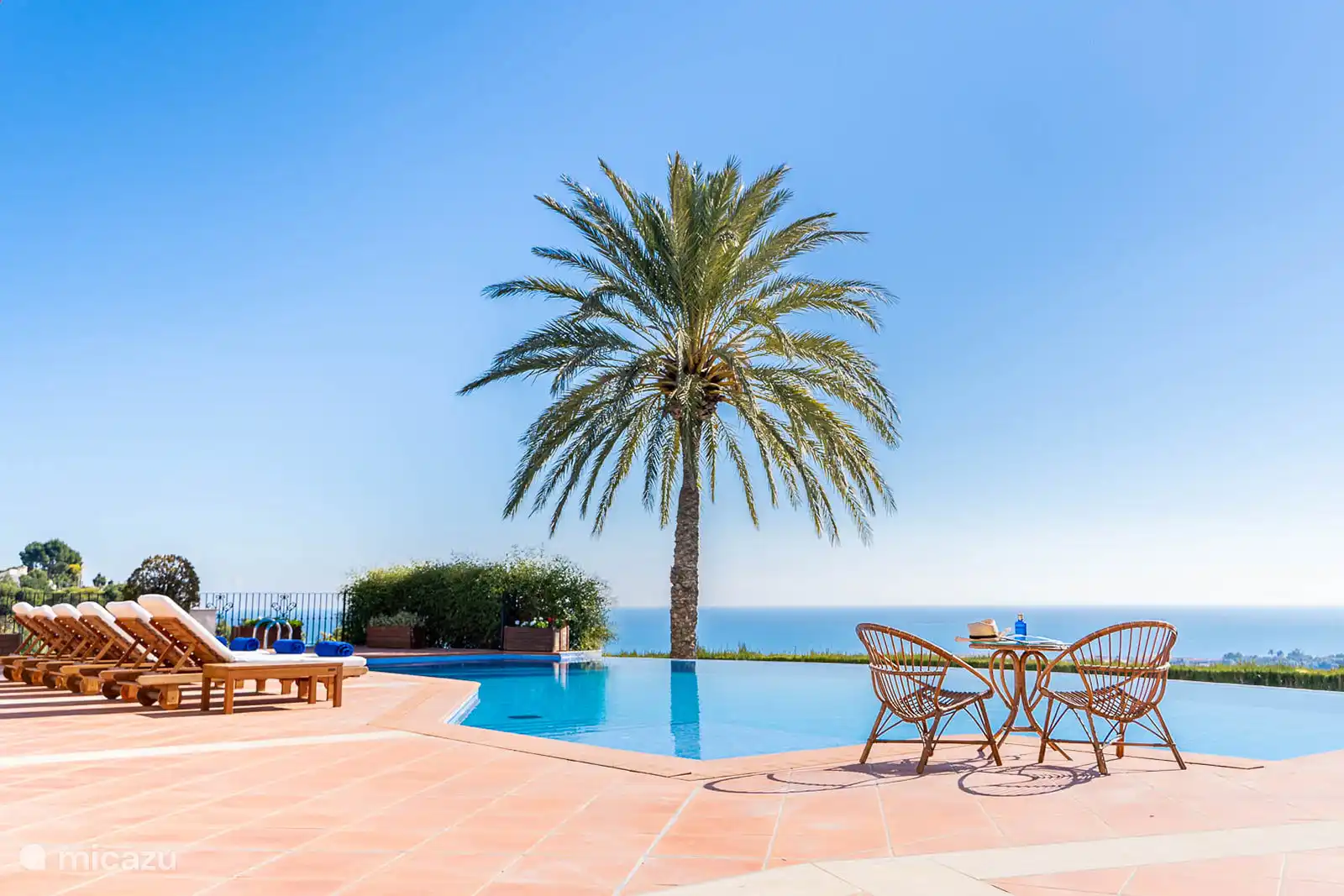 Belle et grande piscine, vue mer, terrasse avec chaises longues. Salon extérieur et lounge sur la terrasse couverte. 