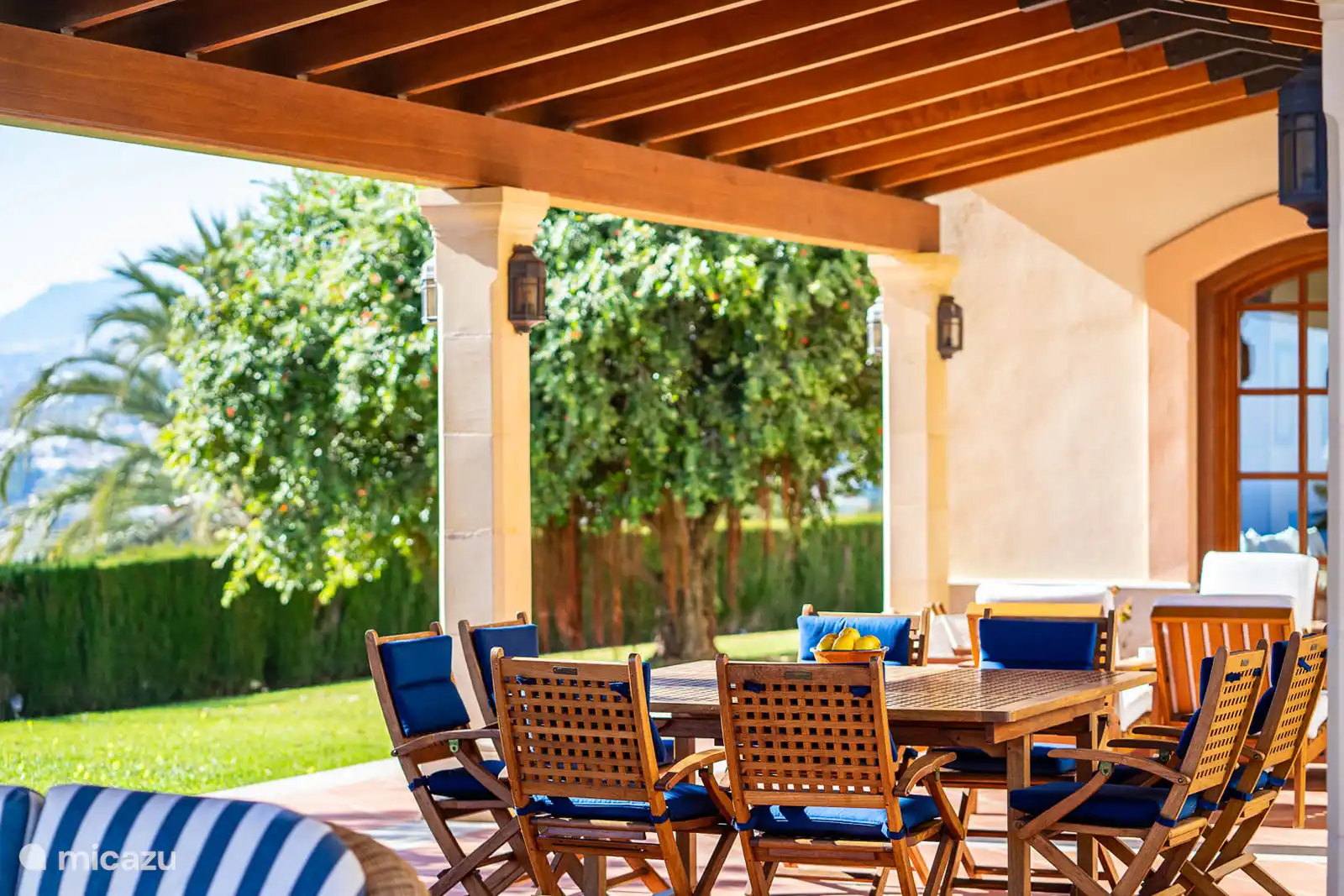 Salon extérieur sous la terrasse couverte, face à la piscine et la vue panoramique.