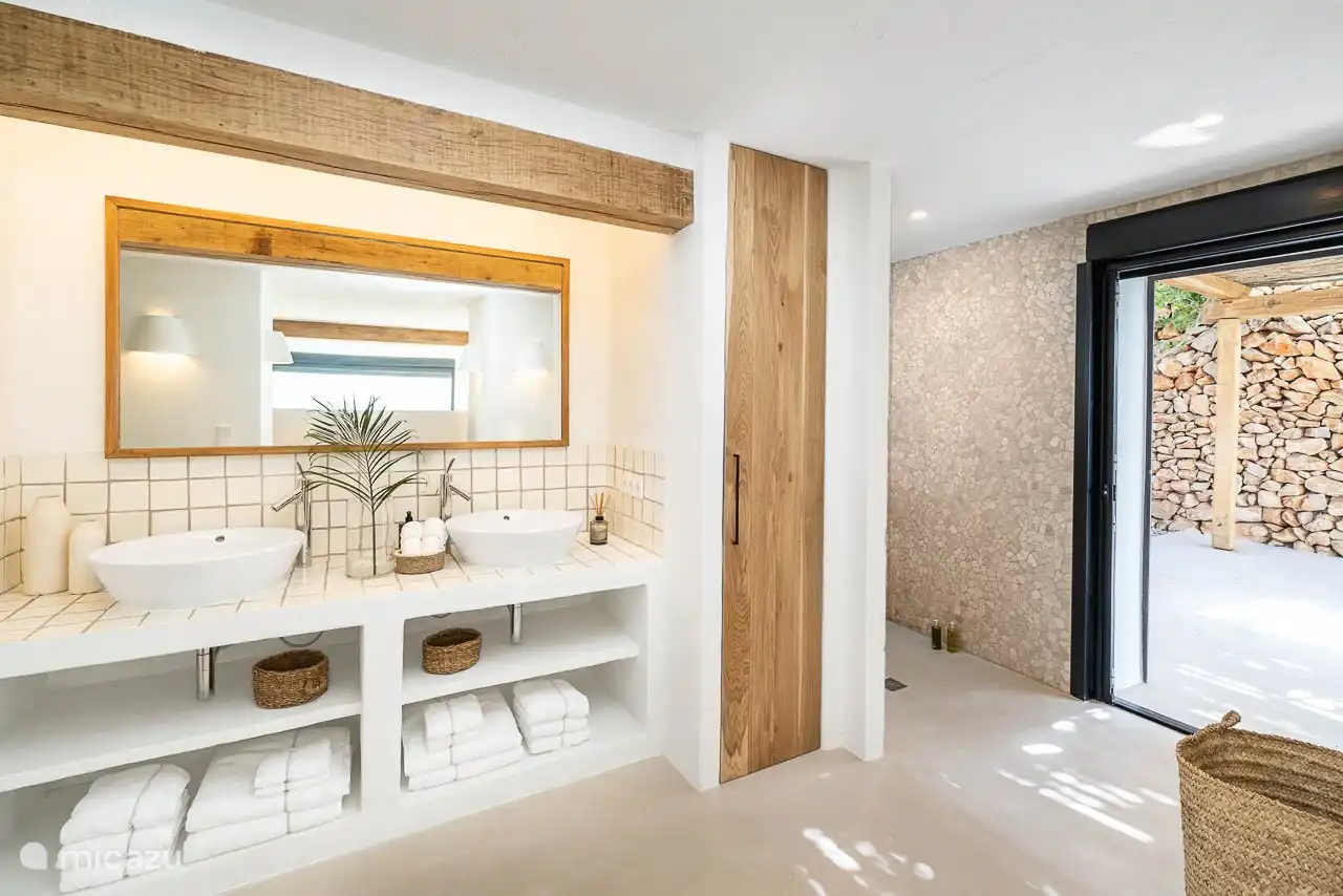 En-suite bathroom with shower, double sink, hairdryer, towels, products. 