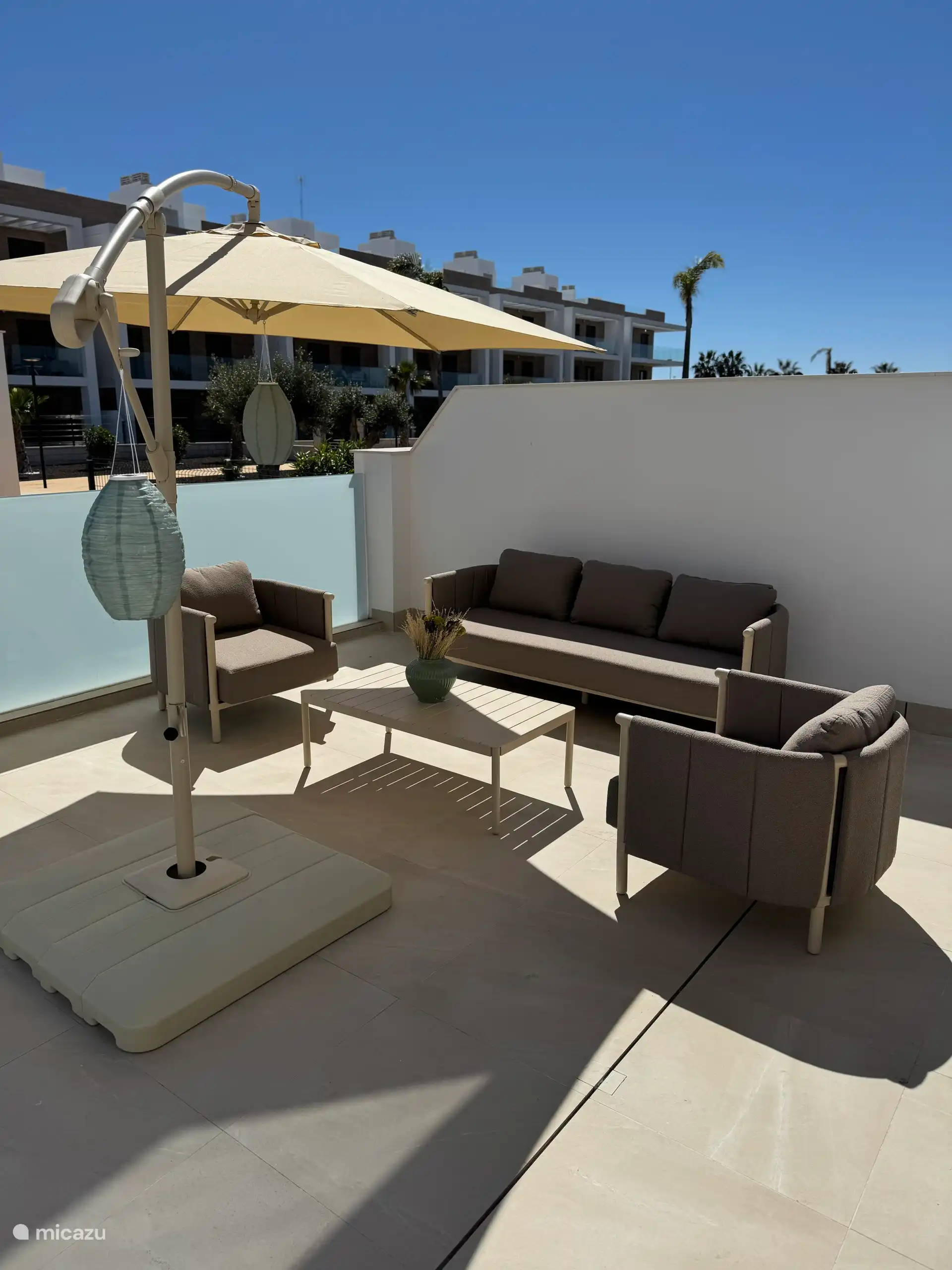 Juego de salón con tapicería bouclé y una gran sombrilla. 