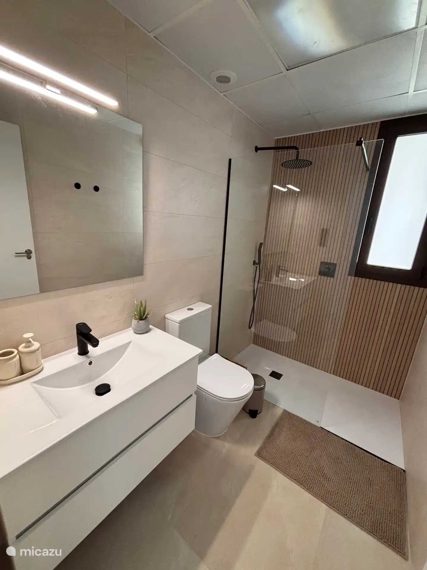 Primer baño con inodoro, muebles y una ducha de lluvia preciosa. 