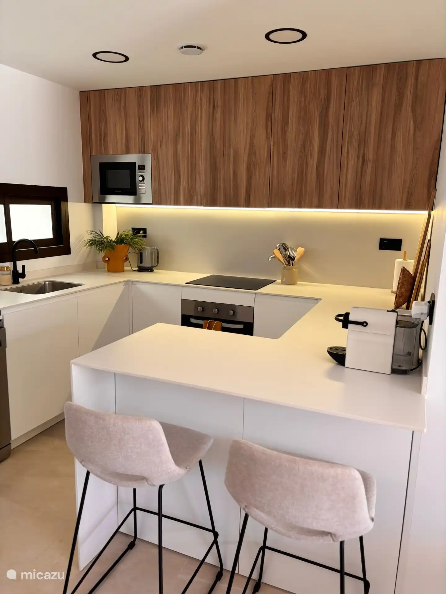 Cocina con lavadora, nevera-congeladora, lavavajillas, microondas, horno, tetera y cafetera. 