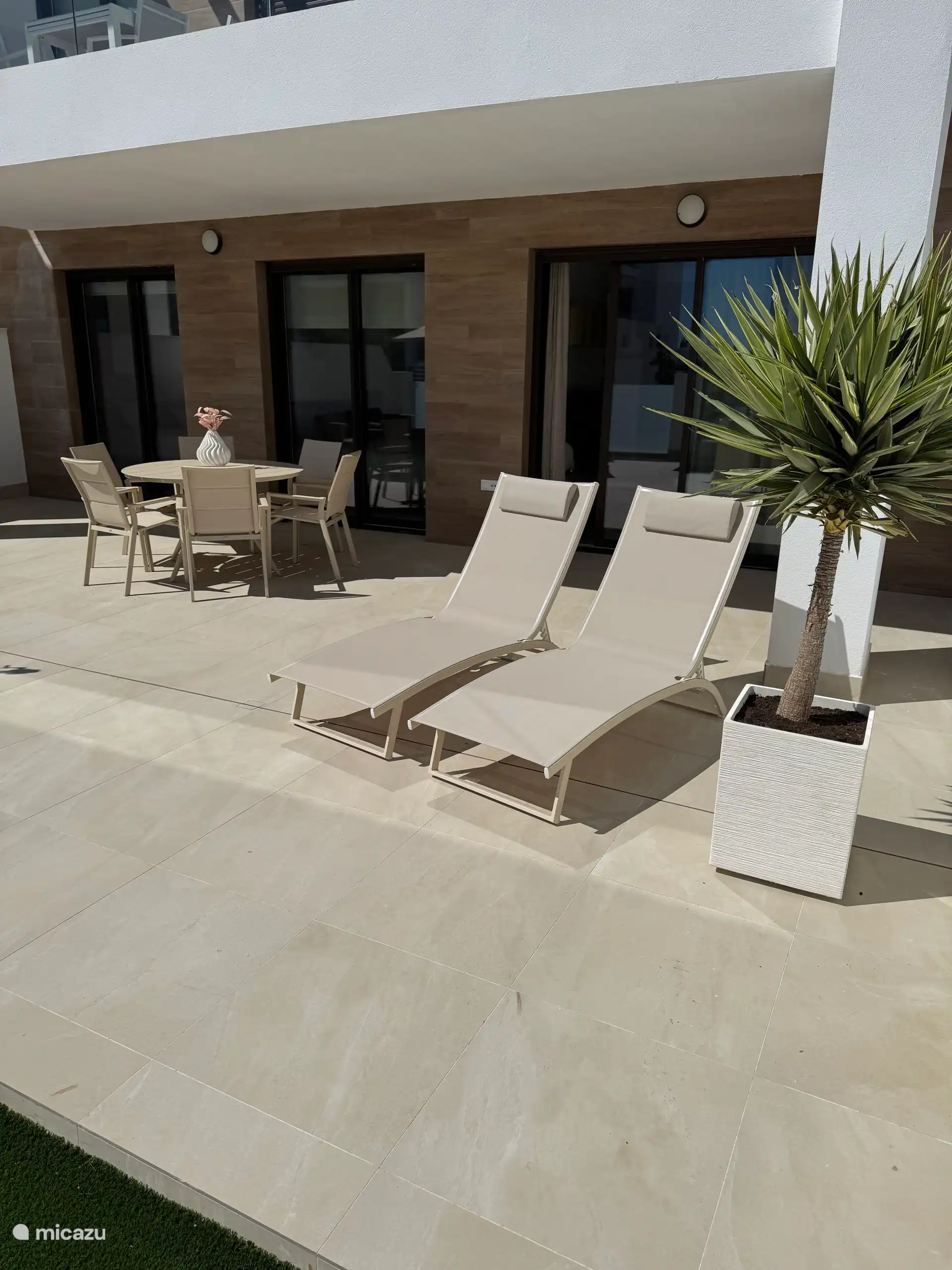 Mesa de jardín y sillas y dos cómodas tumbonas. 