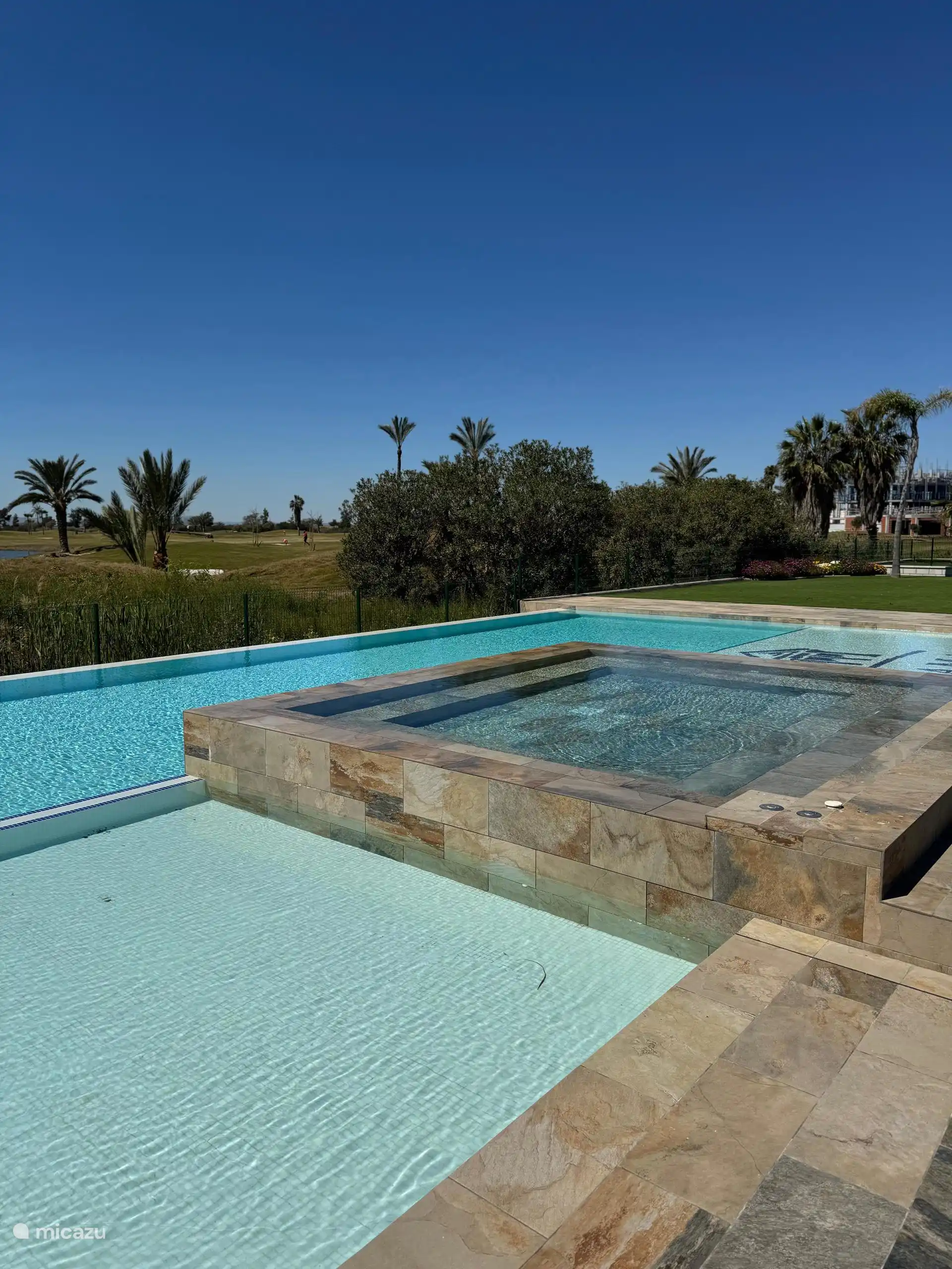 Piscina infinita con vistas al precioso campo de golf ajardinado. 