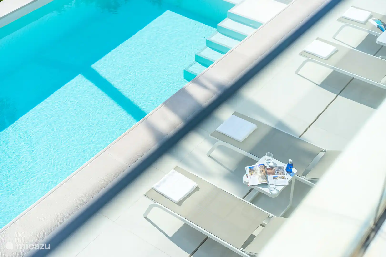 Swimming pool surrounded by a terrace with sun loungers, sea view.
