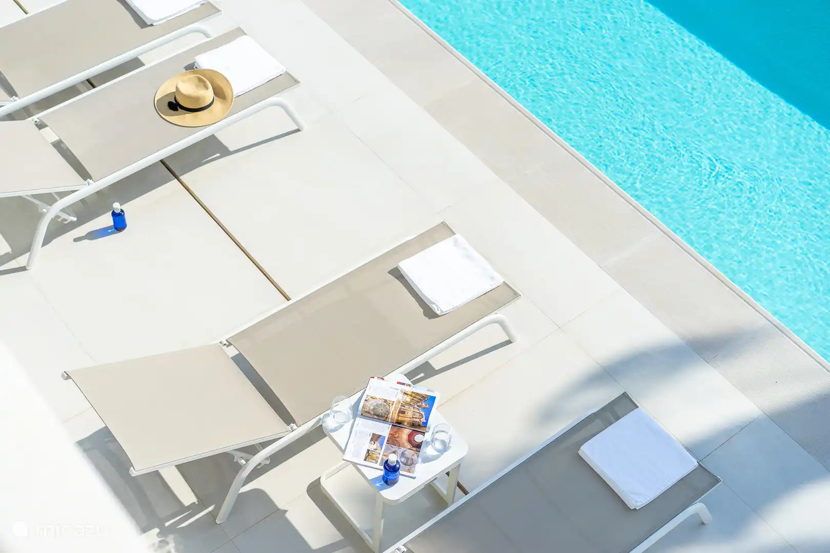 Swimming pool surrounded by a terrace with sun loungers, sea view.