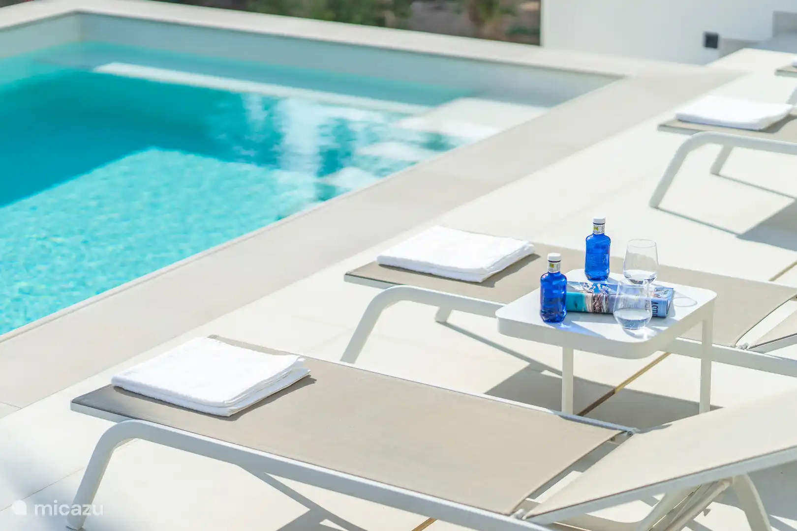 Swimming pool surrounded by a terrace with sun loungers, sea view.