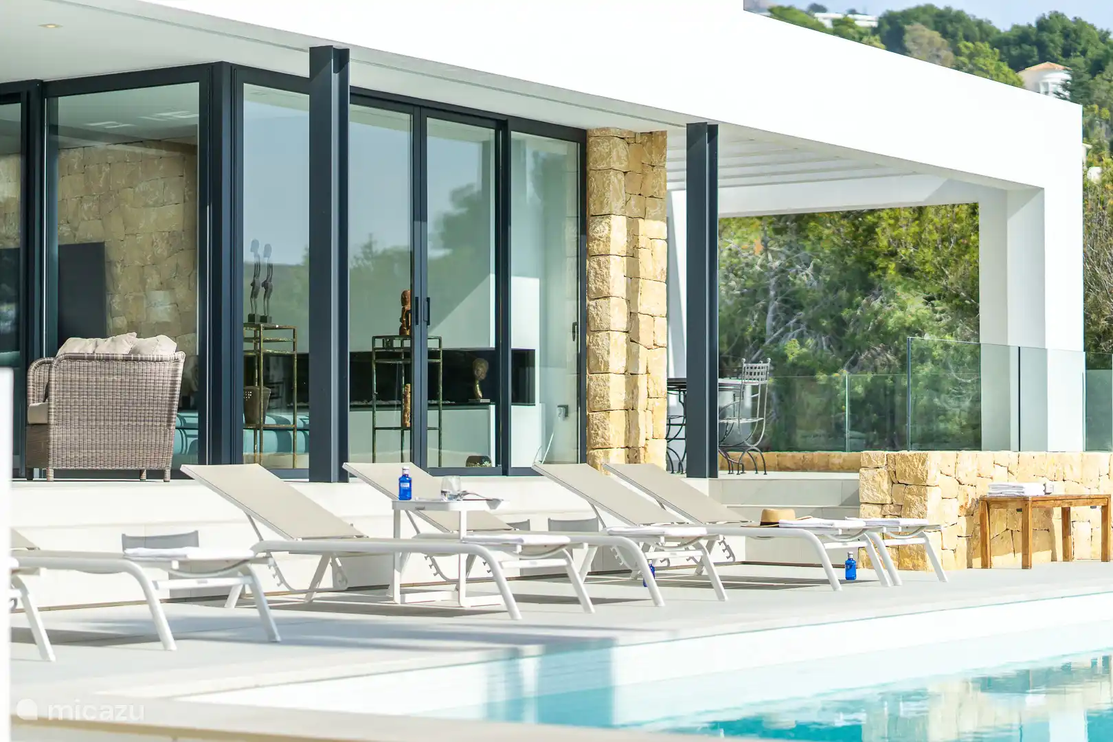 Swimming pool surrounded by a terrace with sun loungers, sea view.