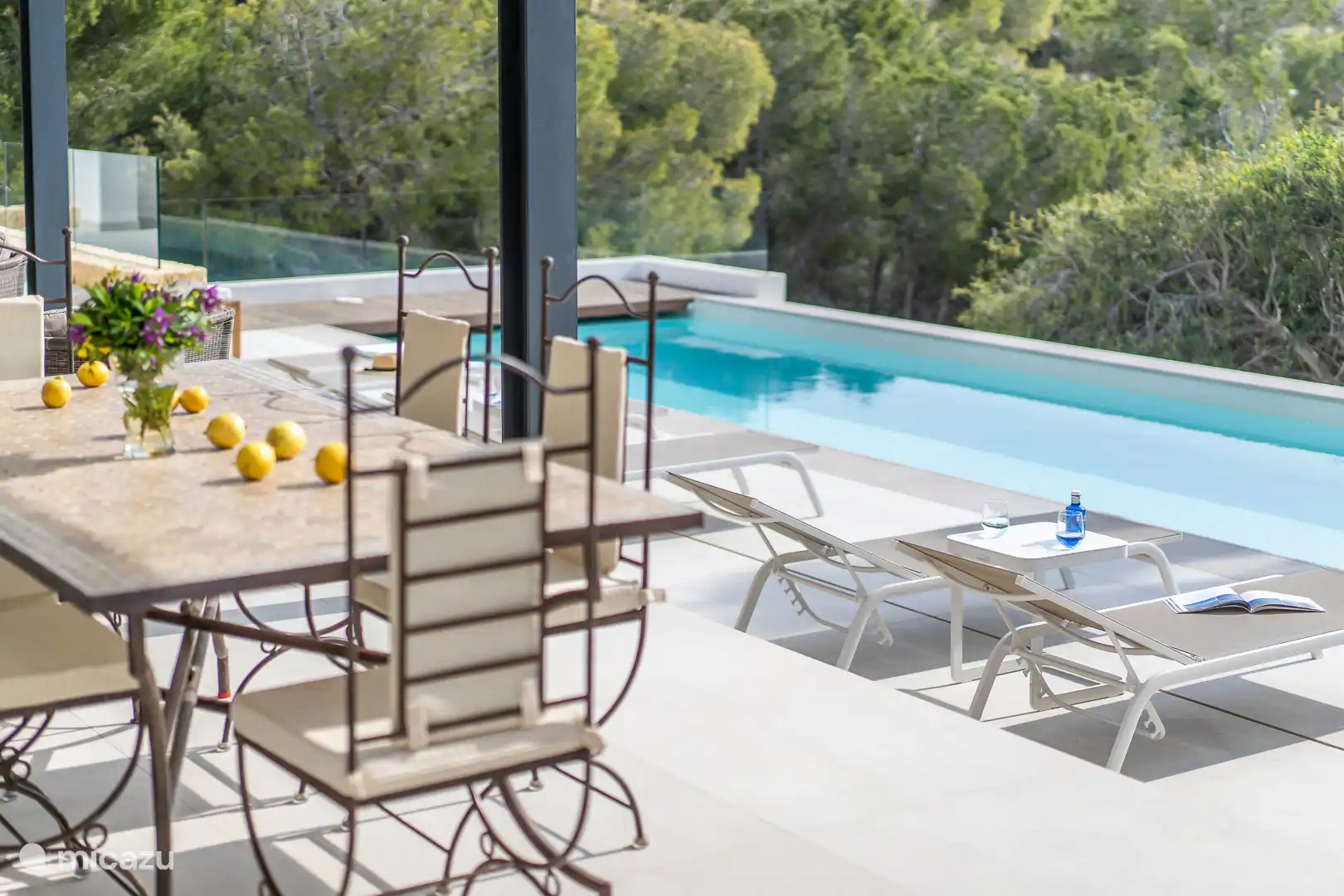 Swimming pool surrounded by a terrace with sun loungers and a garden, sea view, dining table.