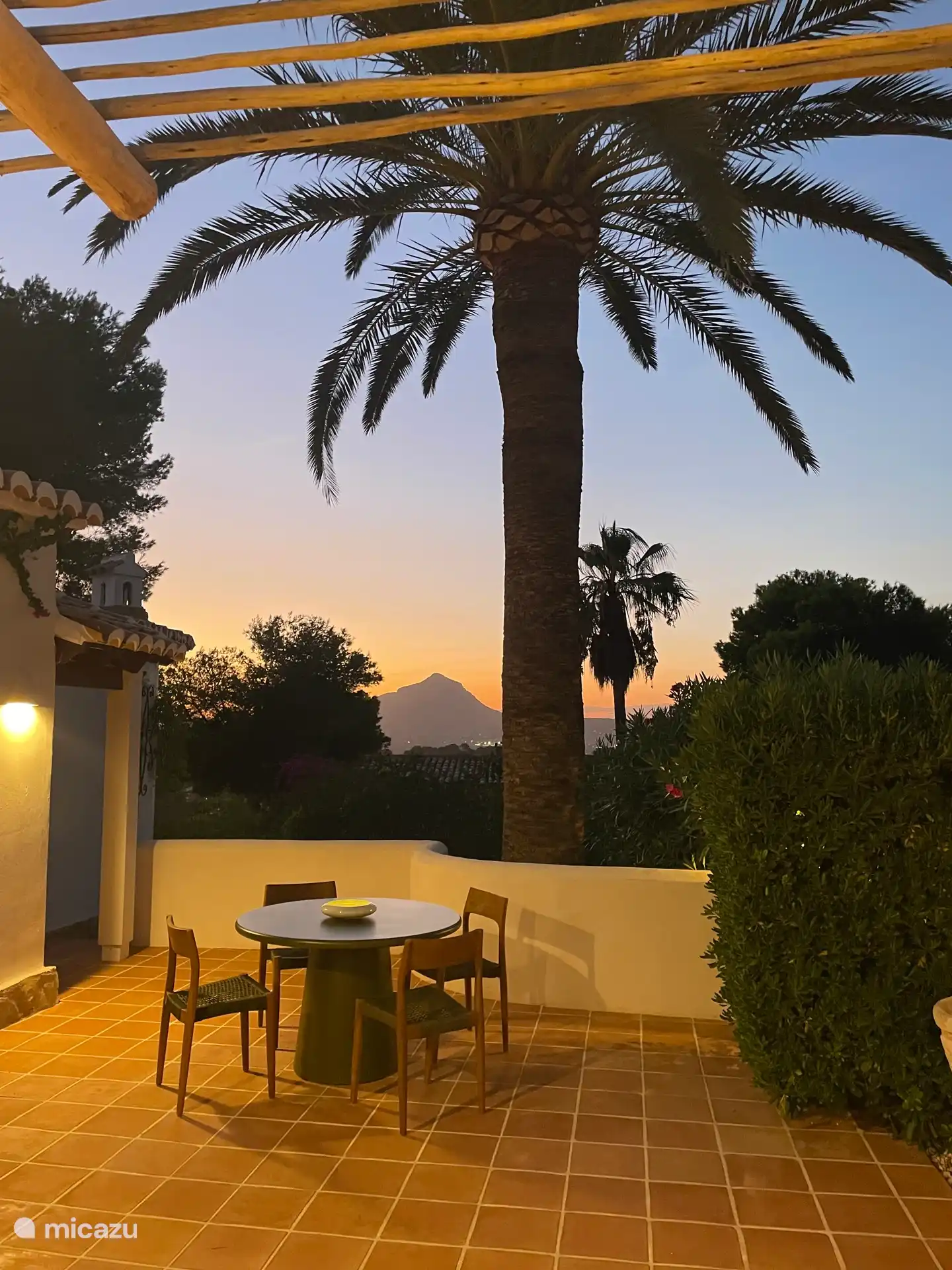 Uitzicht vanaf het zonneterras bij de entree van het huis bij zonondergang.