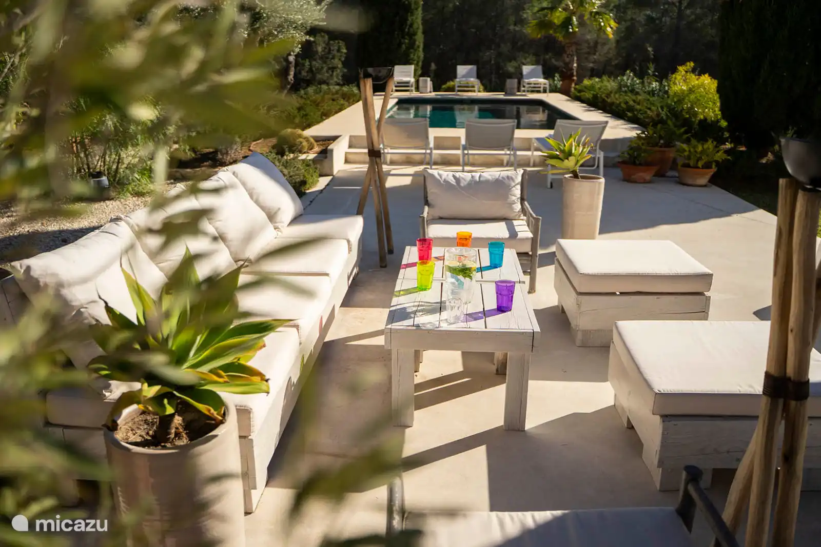 Swimming pool surrounded by a terrace with sun loungers, garden with trees, nature and mountain views, outdoor lounge.