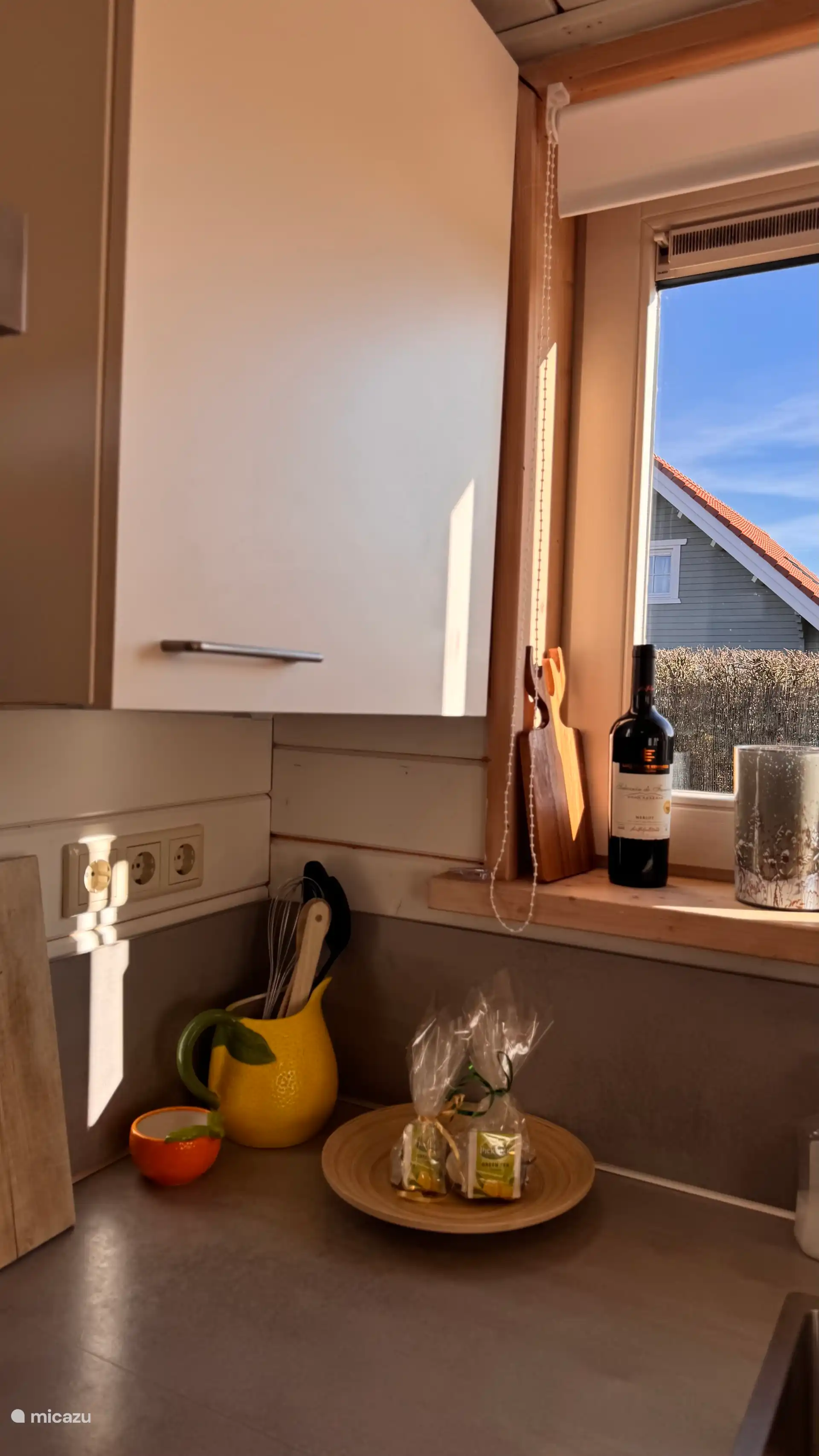 Gezellige keukenhoek waar warm zonlicht naar binnen valt. Houten accenten en zachte kleuren zorgen voor een sfeervolle plek om rustig te koken en te genieten.